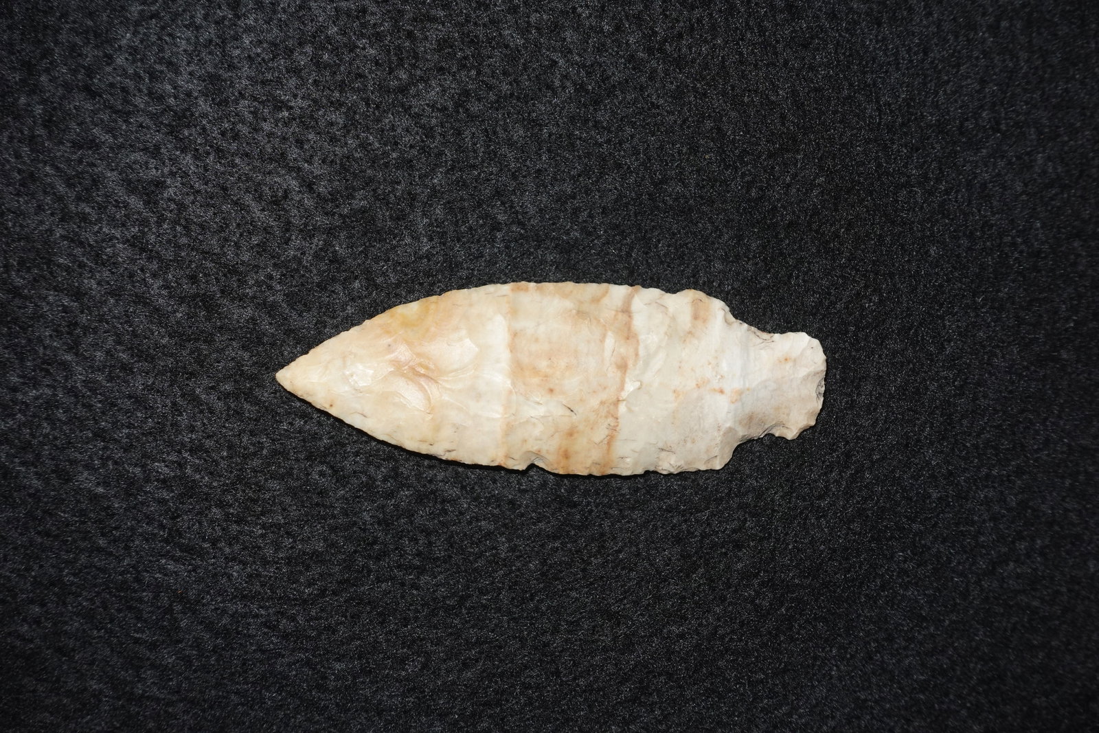 Neosho: Neosho-style flaked stone projectile point with an elongated lanceolate form and a slightly contracting base. Cream and tan stone exhibits pronounced flake scars on both faces and clear bifacial