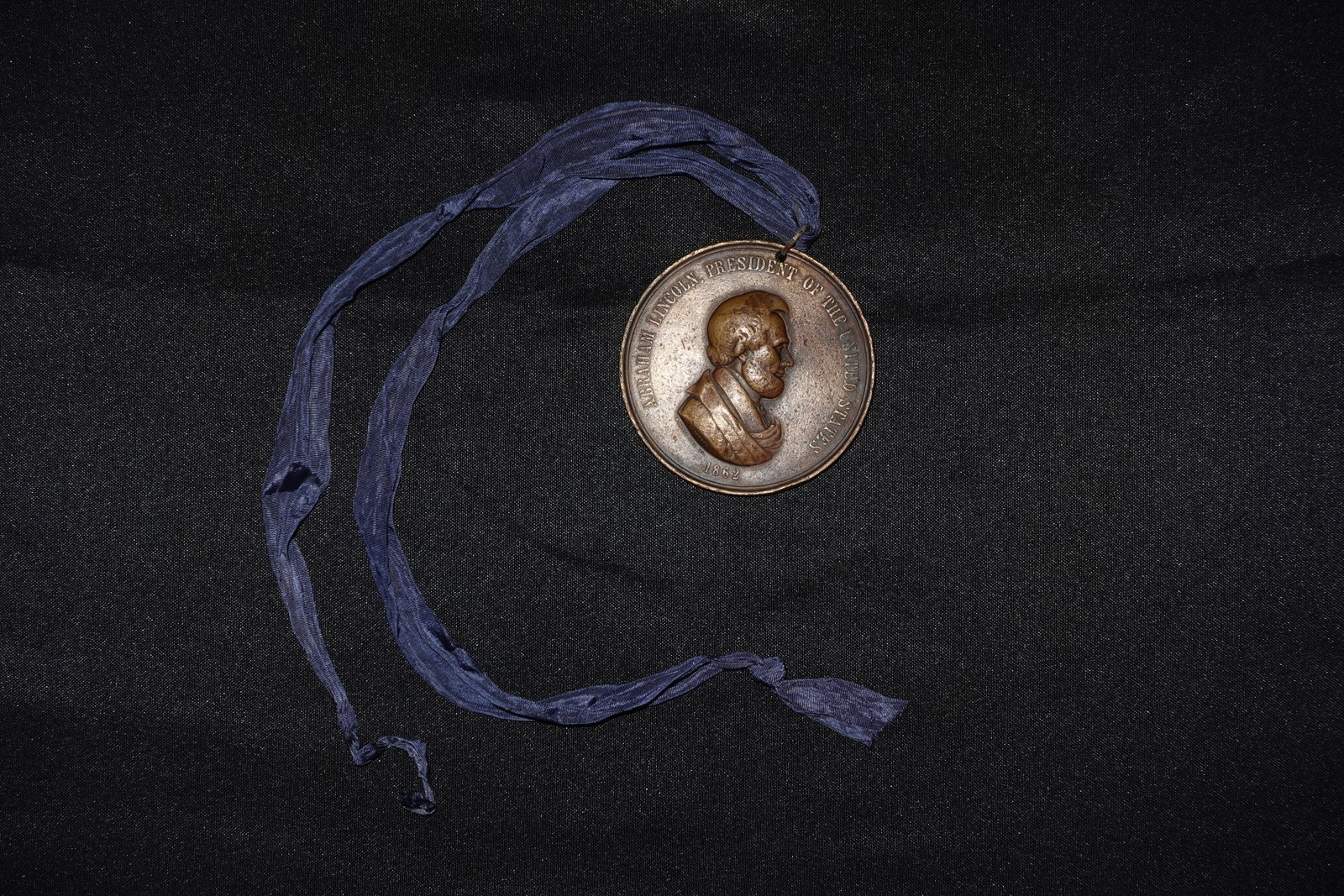 Peace Medal stamped "Red Horse": Bronze circular medallion suspended from a faded blue silk ribbon, exhibiting warm brown and copper tones. Obverse features a high-relief bearded male bust with a surrounding legend that includes the