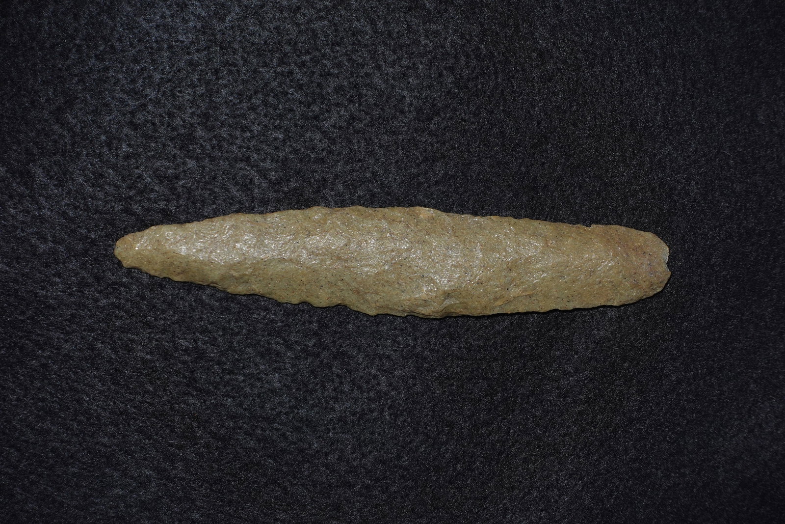Lerma Blade: Long, narrow Lerma-style stone blade composed of pale green-tan chert with a subtly glossy, granular surface. Bifacial flaking produces a tapered profile with a pointed tip and visible flake scars