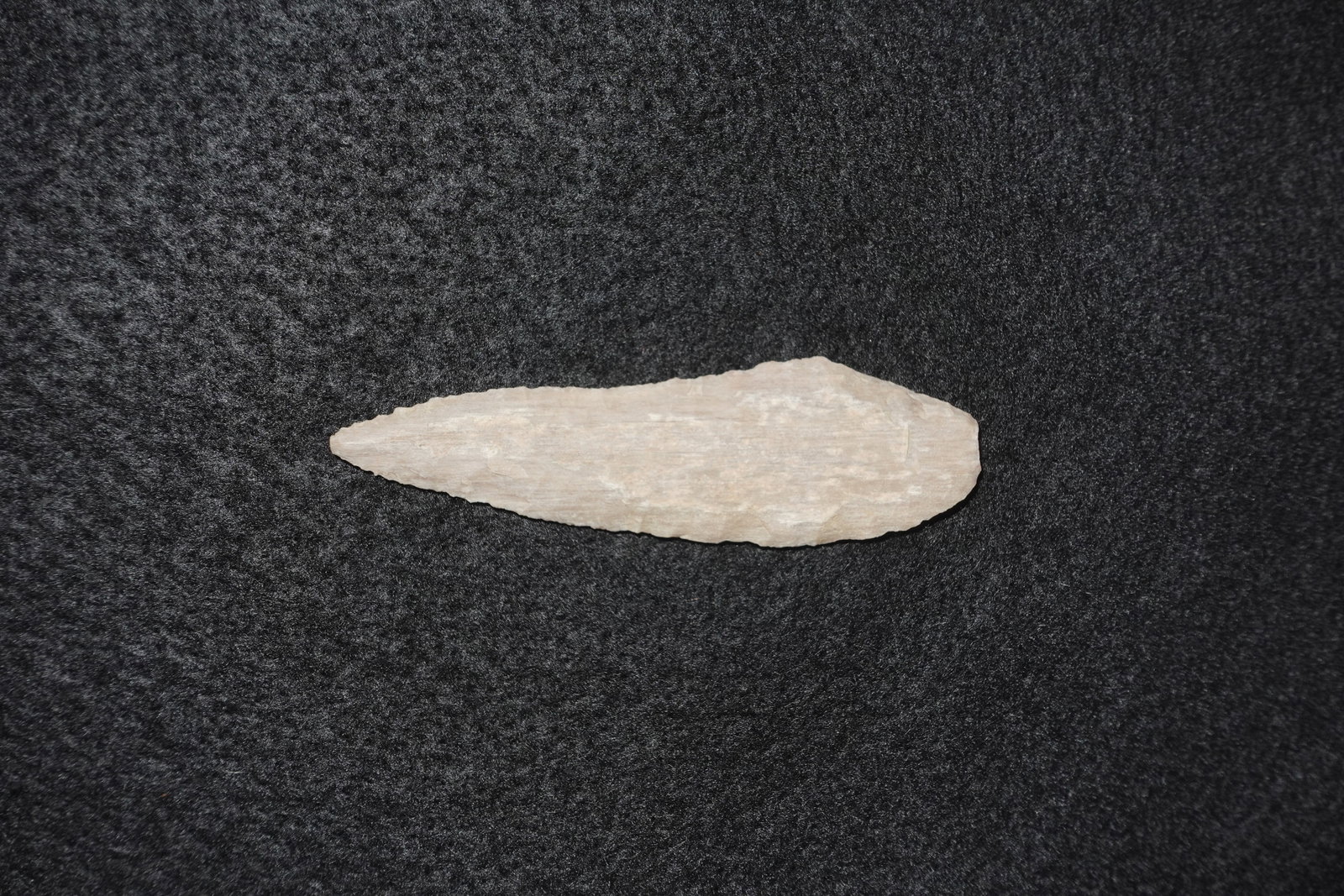 Haskett: Long lanceolate point worked from pale western agate with visible bifacial flake scars. Fine marginal retouch along one edge creates a subtly serrated cutting profile while the opposite edge shows bro
