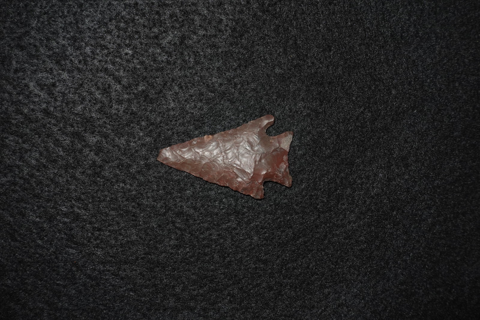 Corner Notch Point: Corner-notched stone point with a triangular blade and distinct basal notches. Deep reddish-brown coloration with extensive flake scars and visible percussion/pressure retouch across the faces.