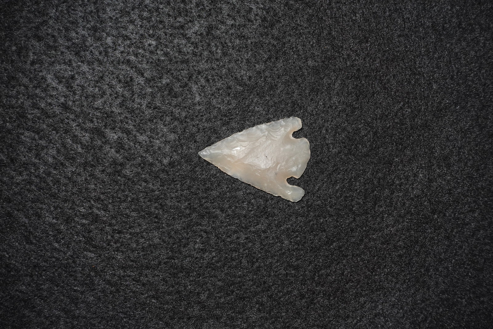 Agate Basal Notched Point: Translucent agate projectile point with pronounced basal notches and a broad triangular blade. Fine pressure flaking and concentric ripple-like flake scars cover both faces, producing a glossy