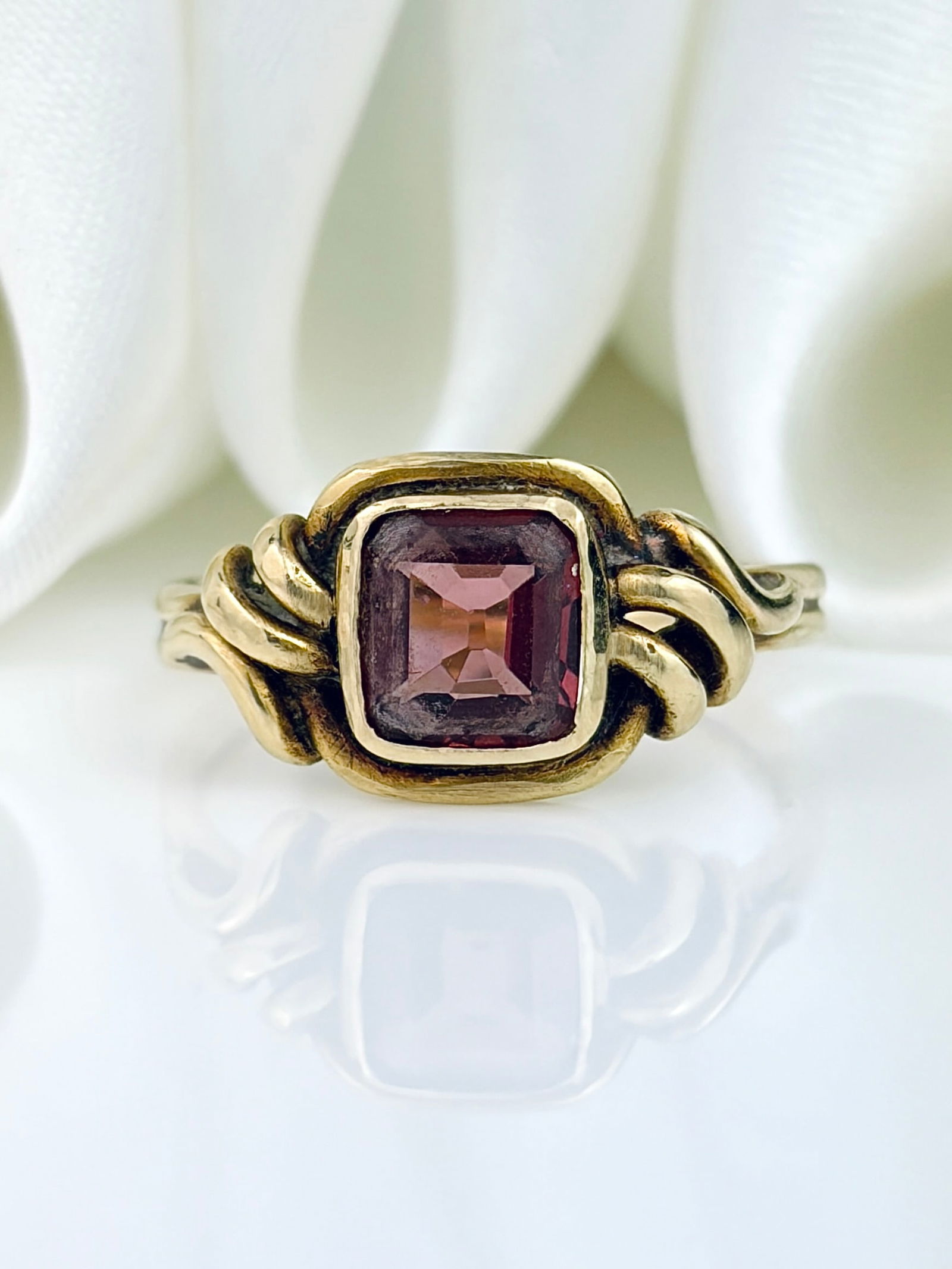 VINTAGE 18CT YELLOW GOLD GARNET KNOT DETAIL RING: VINTAGE 18CT YELLOW GOLD GARNET KNOT DETAIL RING Wonderful ring with a central square cut diamond set into a knot style! Weight: 2.42g Size: UK J, US 5.25, Width 8mm, height off finger
