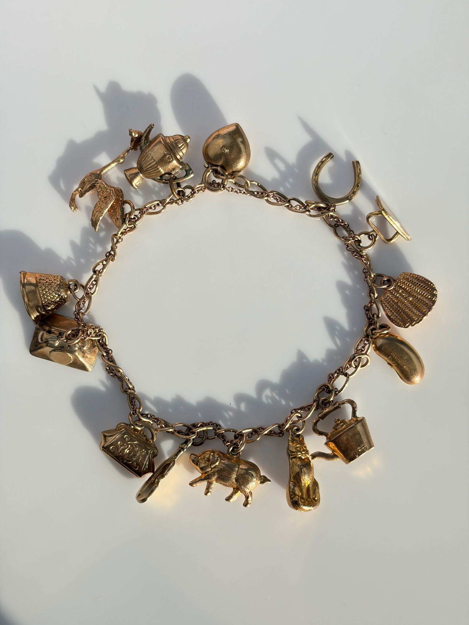 VINTAGE 9CT YELLOW GOLD CHARM BRACELET HORSESHOE, BEAN, HEART ETC: VINTAGE 9CT YELLOW GOLD CHARM BRACELET HORSESHOE, BEAN, HEART ETC Weight: 14.27g Size: Length 19.4cm Materials: 9ct gold Hallmarks: Each link stamped 9.375 Condition: Very good
