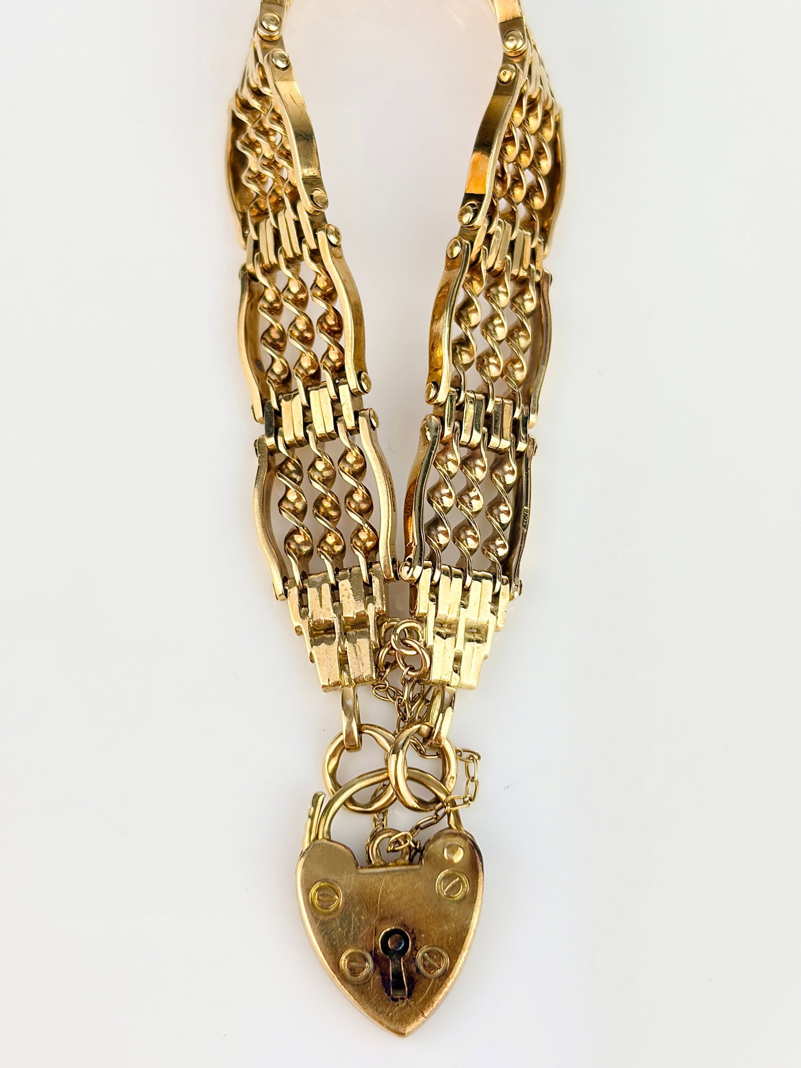 ANTIQUE 9CT YELLOW GOLD CHUNKY GATE BRACELET WITH HEART PADLOCK: ANTIQUE 9CT YELLOW GOLD CHUNKY GATE BRACELET WITH HEART PADLOCK Stunning twisted interlocking links! Weight: 22.23g Size: Length 18cm, width 10mm Materials: 9ct gold Hallmarks: Stamped