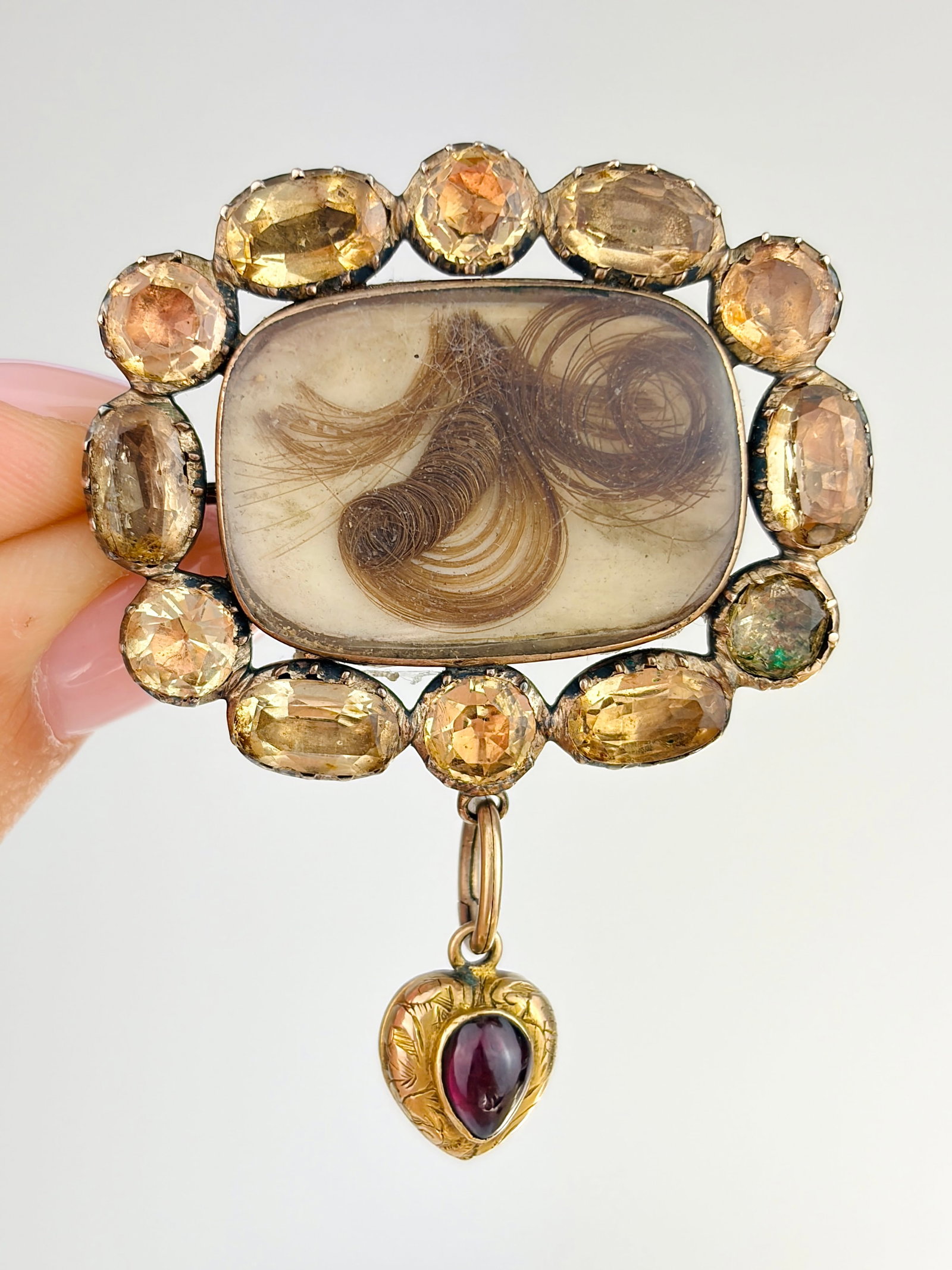 ANTIQUE GOLD MOURNING DOUBLE LOCKET HAIR BROOCH WITH TOPAZ HALO AND GARNET HANGING HEART: ANTIQUE GOLD MOURNING DOUBLE LOCKET HAIR BROOCH WITH TOPAZ HALO AND GARNET HANGING HEART Stunning pale orange topaz stones surrounding a hair locket, with a dangling garnet heart to cherish a