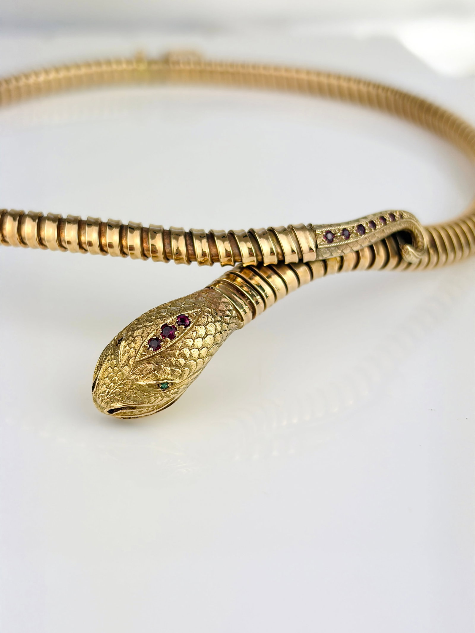 VINTAGE 9CT YELLOW GOLD SNAKE GAS PIPE NECKLACE WITH EMERALD EYES AND RUBY HEAD: VINTAGE 9CT YELLOW GOLD SNAKE GAS PIPE NECKLACE WITH EMERALD EYES AND RUBY HEAD AND TAIL Show stopping coiled snake necklace! Weight: 33.14g Size: Length 43.5cm, width 6mm Materials: 9ct