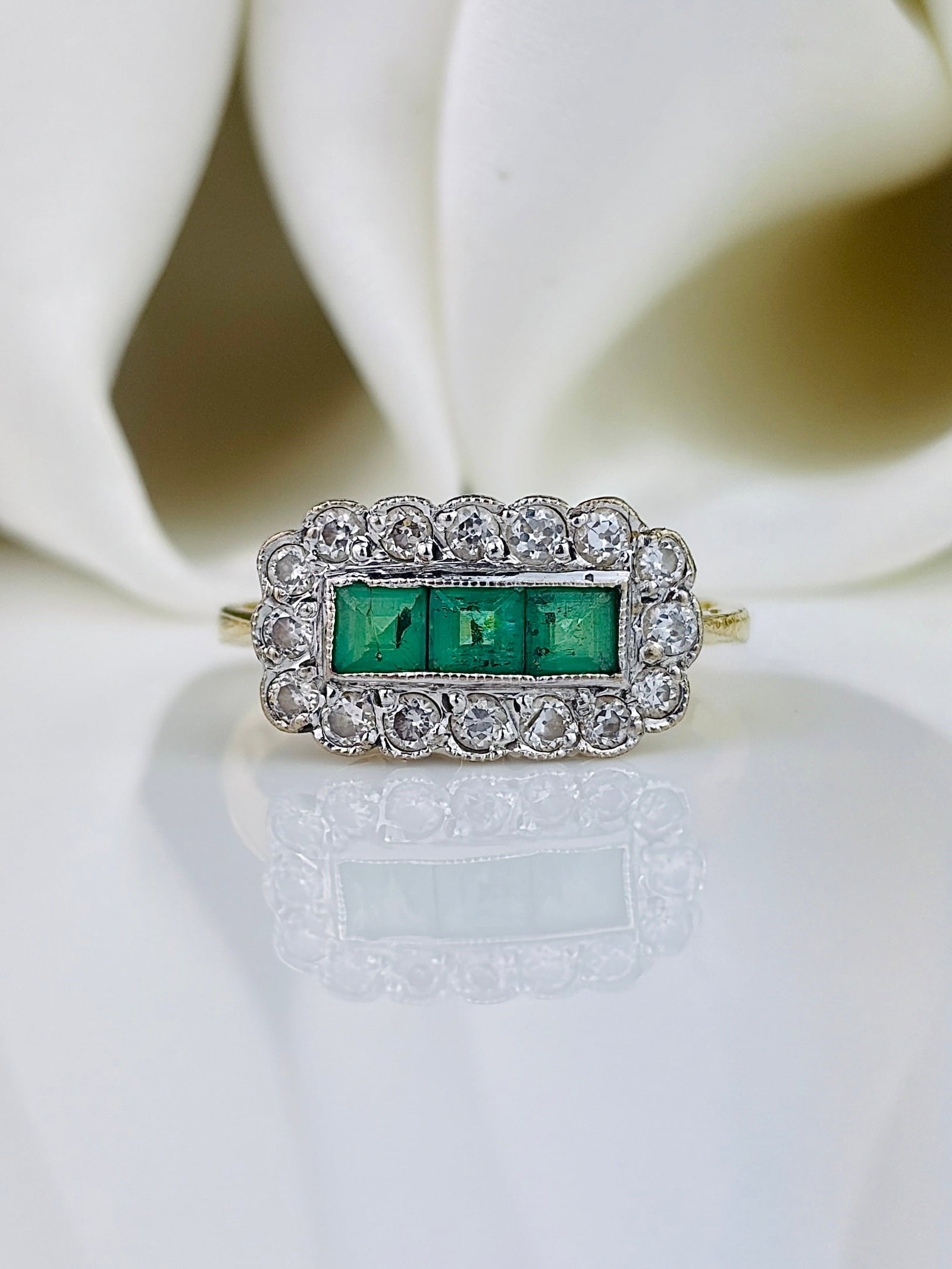 Emerald and Diamond 18ct Gold Three Stone Cluster Ring: Emerald and Diamond 18ct Gold Three Stone Cluster Ring An exquisite three stone ring with square set emeralds surrounded by a halo of diamonds. The diamond total is 48pts, and are set in platinum, an