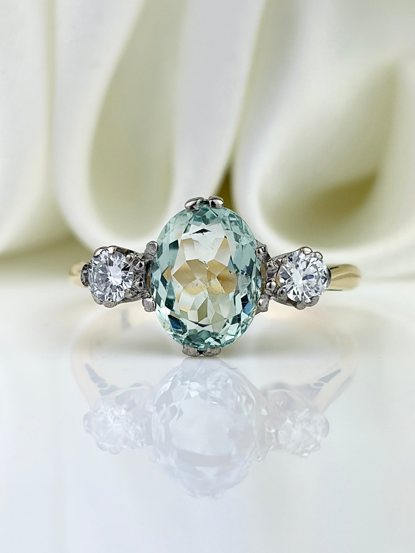 VINTAGE 18CT YELLOW GOLD AND PLATINUM AQUAMARINE AND DIAMOND 3 STONE RING: VINTAGE 18CT YELLOW GOLD AND PLATINUM AQUAMARINE AND DIAMOND 3 STONE RING Stunning vintage ring featuring an oval cut aquamarine flanked by two round diamonds set in platinum, with a gold shank!