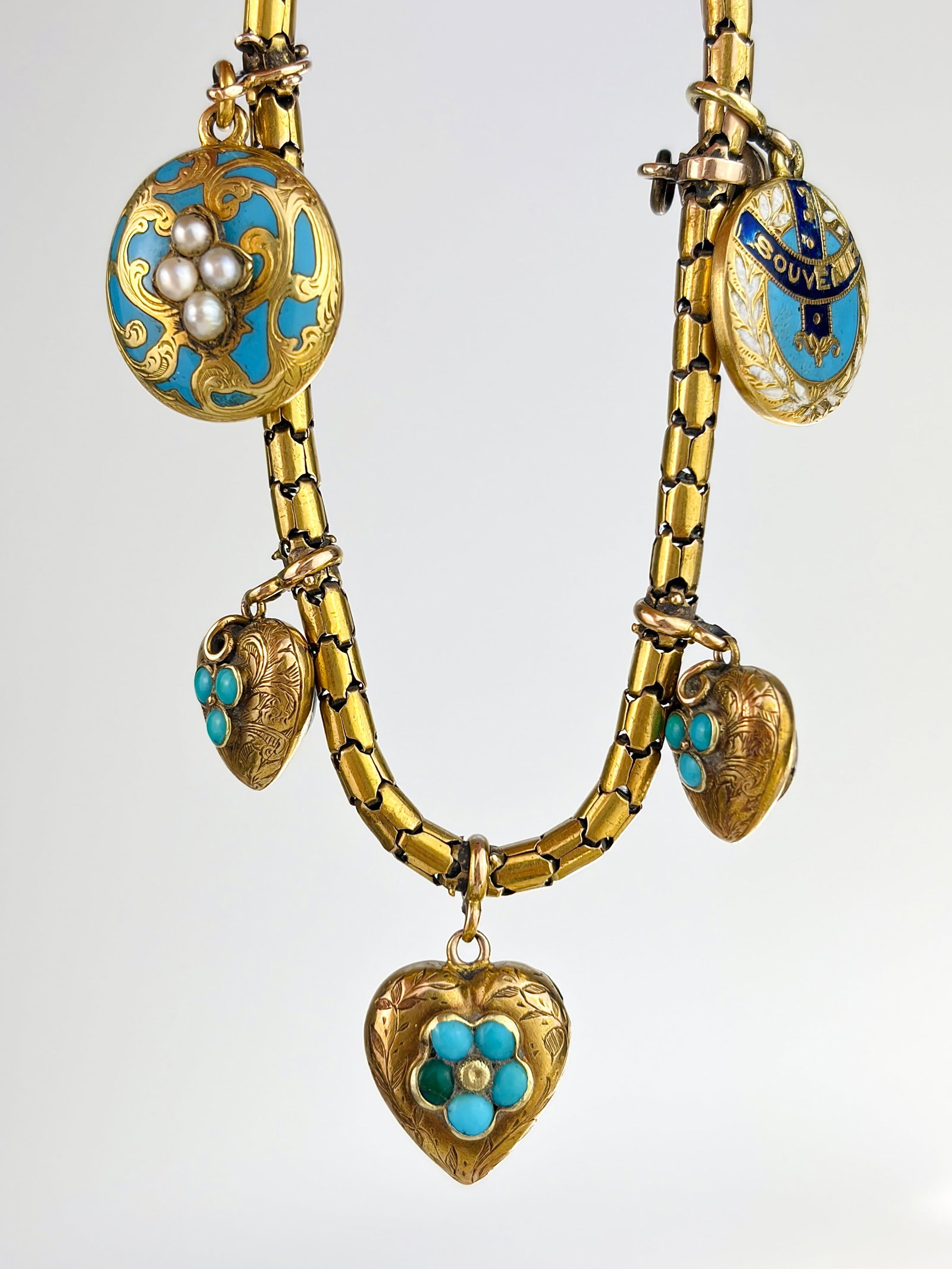 ANTIQUE VICTORIAN 18CT YELLOW GOLD TURQUOISE HEART, AND BLUE ENAMEL AND PEARL CHARM BRACELET: ANTIQUE VICTORIAN 18CT YELLOW GOLD TURQUOISE HEART, AND BLUE ENAMEL AND PEARL, TOPAZ CHARM BRACELET Incredible bracelet with a gold mesh chain adorned with turquoise hearts, and blue enamel charms, al