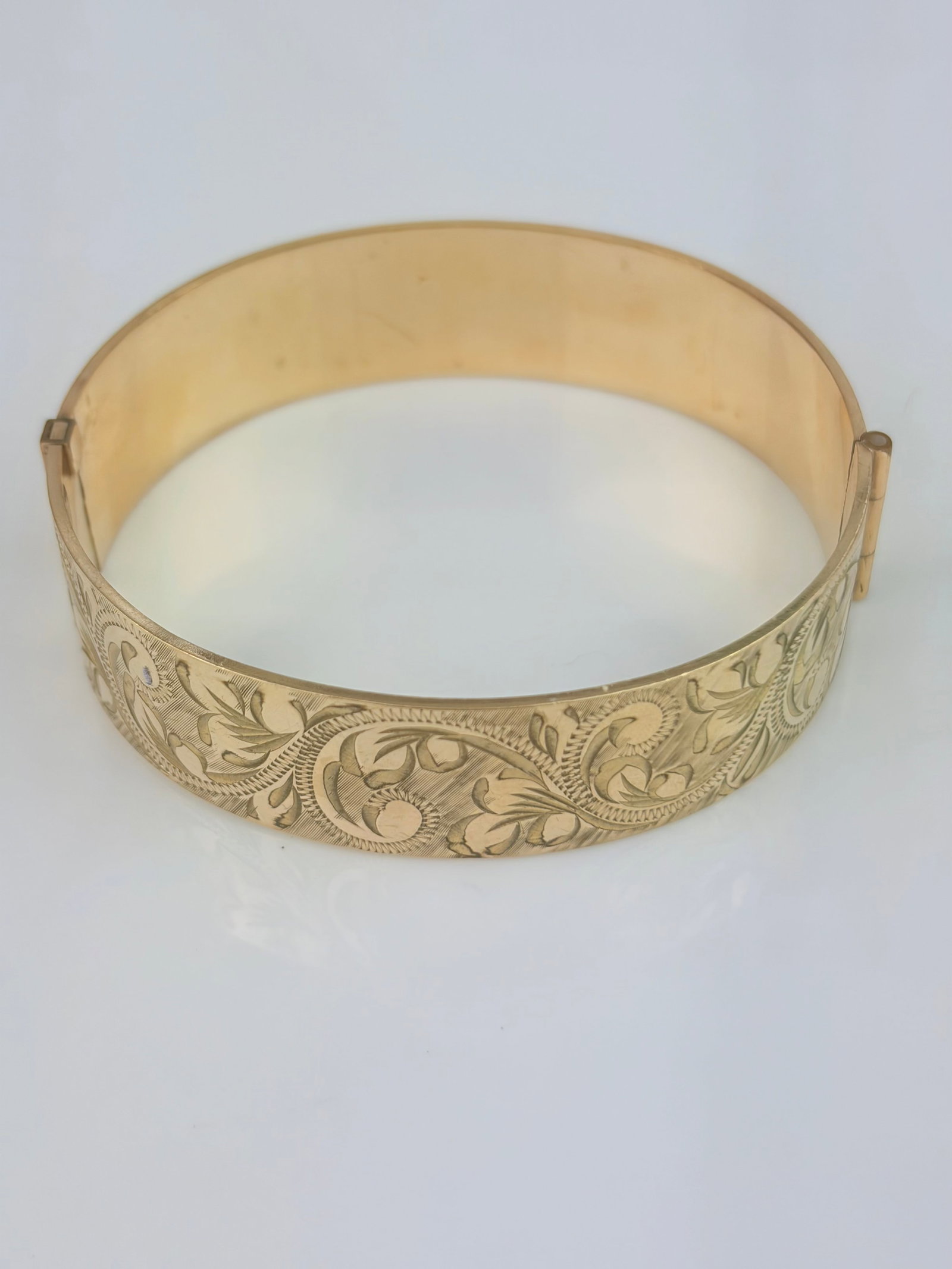 VINTAGE 9CT ROLLED GOLD SWIRL BANGLE BRACELET: VINTAGE 9CT ROLLED GOLD SWIRL BANGLE BRACELET Weight: 28.37g Size: 52x57mm, width 15mm Materials: 9ct rolled gold Hallmarks: Stamped 50 micron 9ct RG Condition: Very good overall