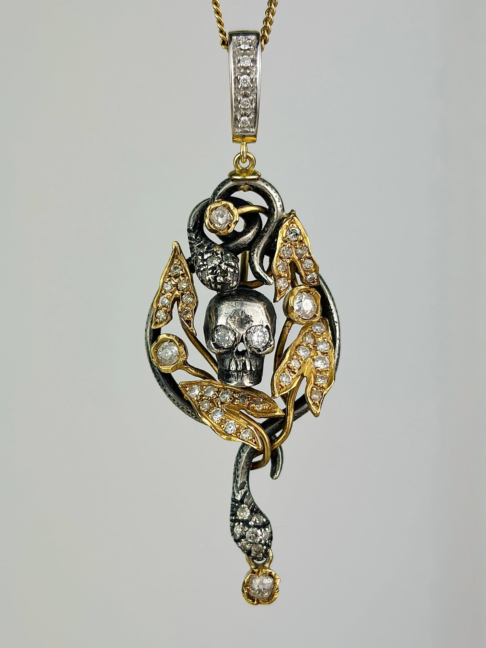 INCREDIBLE 14CT YELLOW GOLD AND SILVER DIAMOND SKULL AND SNAKES PENDANT: INCREDIBLE 14CT YELLOW GOLD AND SILVER DIAMOND SKULL AND SNAKES PENDANT Such a cool pendant! Weight: 12.58g Size: 65x22mm Materials: 14ct gold and silver Hallmarks: None present Condition: