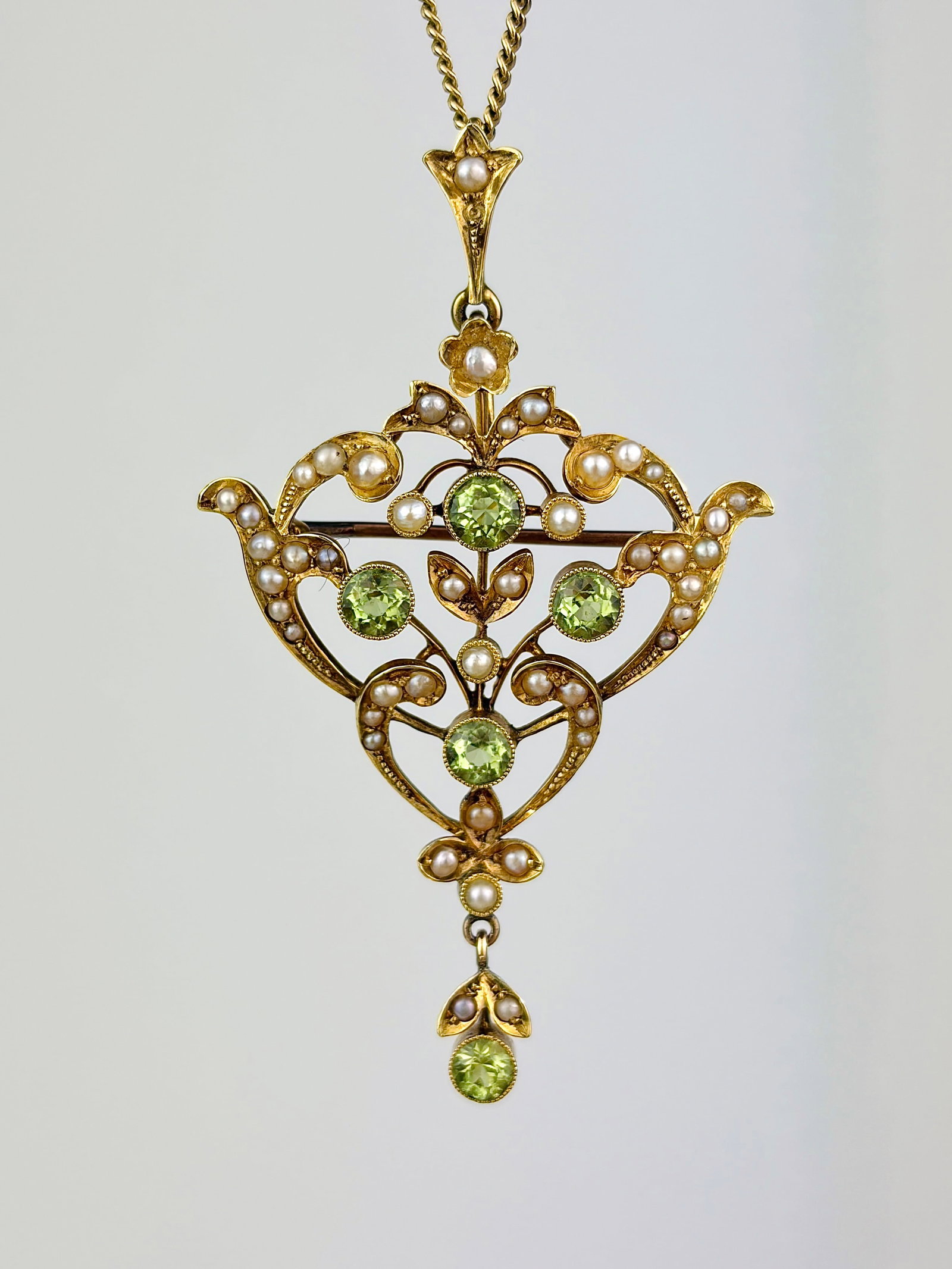 ANTIQUE 15CT YELLOW GOLD PERIDOT AND PEARL BROOCH / PENDANT: ANTIQUE 15CT YELLOW GOLD PERIDOT AND PEARL BROOCH / PENDANT Exquisite ornate pendant! Weight: 4.84g Size: 53x31mm Materials: 15ct gold Hallmarks: Stamped 15ct Condition: Very good overall