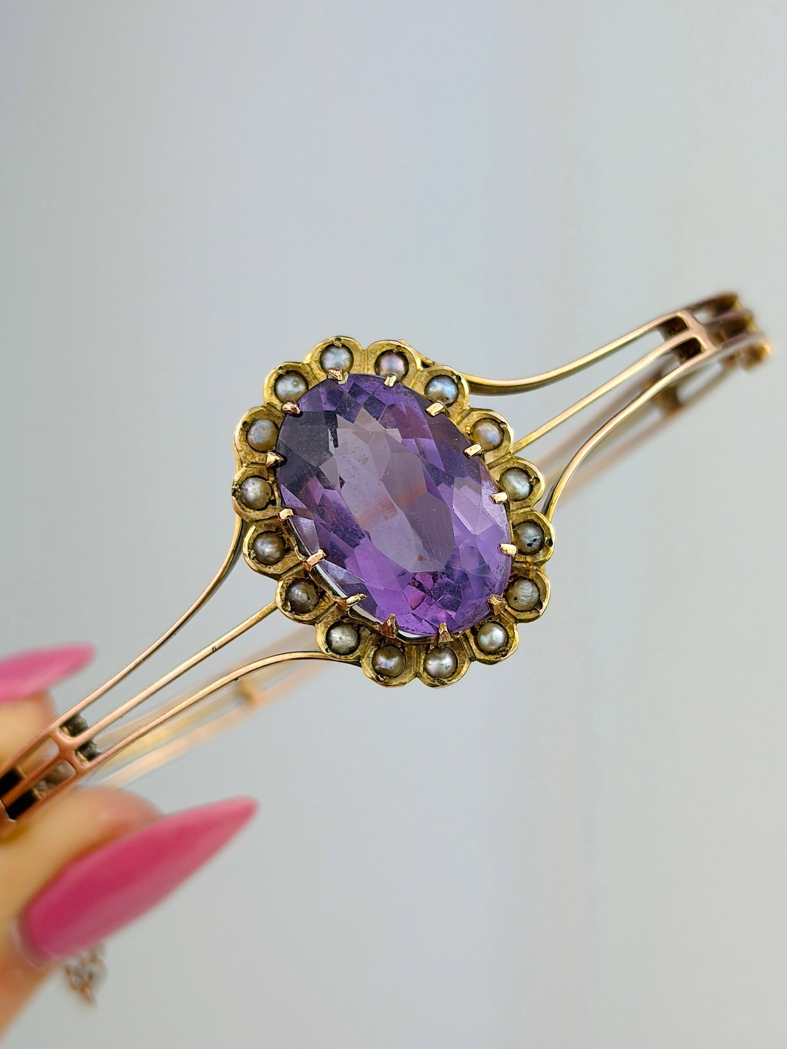 ANTIQUE LARGE AMETHYST AND PEARL GOLD BANGLE / BRACELET: ANTIQUE LARGE AMETHYST AND PEARL GOLD BANGLE / BRACELET This is a stunning antique Victorian era hinged bangle bracelet. It features a large, vibrant oval cut amethyst stone prominently displayed at i