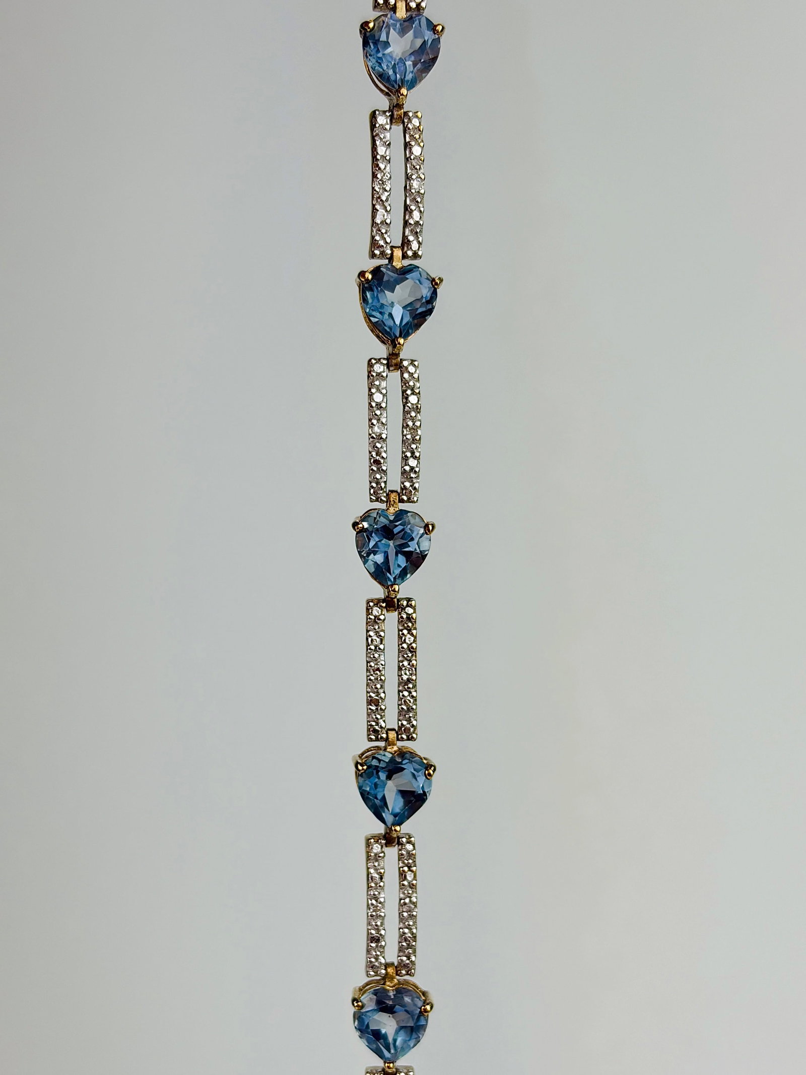 VINTAGE 9CT YELLOW AND WHITE GOLD BLUE TOPAZ HEART BRACELET: VINTAGE 9CT YELLOW AND WHITE GOLD BLUE TOPAZ HEART BRACELET Weight: 7.8g Size: Length 19.5cm, width 6mm Materials: 9ct gold Hallmarks: Stamped 375 Condition: Very good overall condition. Some