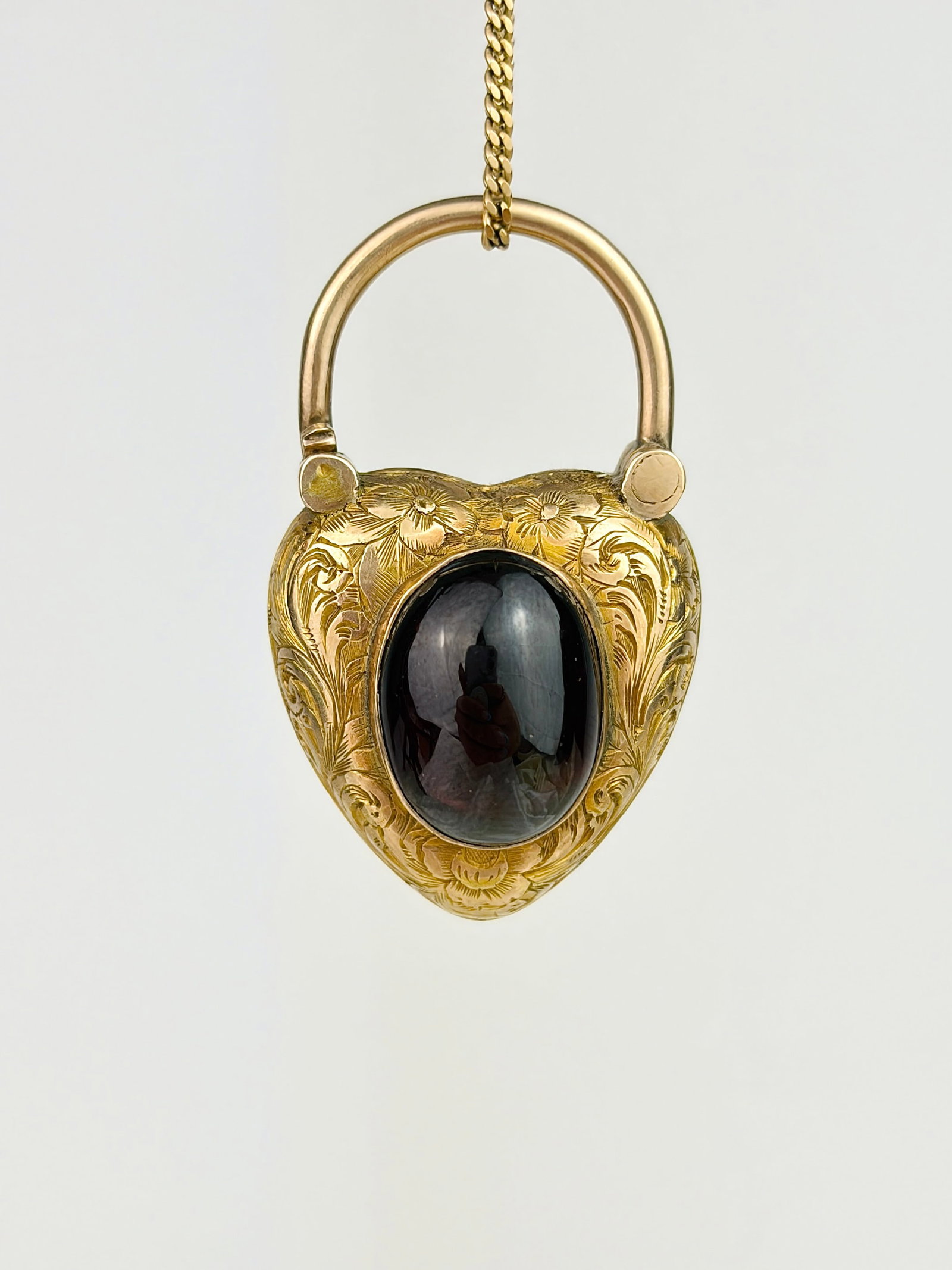 ANTIQUE CABOCHON GARNET FLOWER ENGRAVED HEART PADLOCK WITH LOCKET BACK IN GOLD: ANTIQUE CABOCHON GARNET FLOWER ENGRAVED HEART PADLOCK WITH LOCKET BACK IN GOLD Such a stunning heart padlock with a juicy centre cabochon garnet, surrounded by ornate flower engravings!