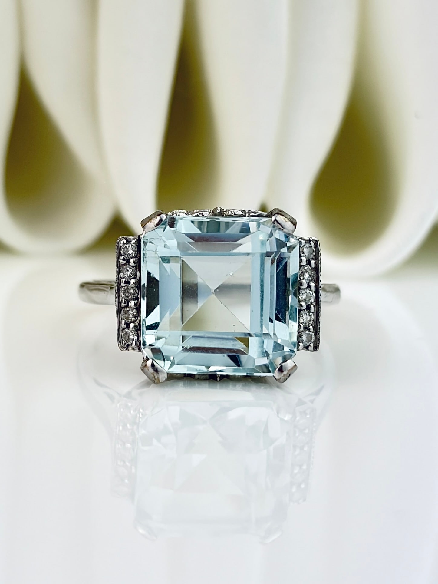 VINTAGE 9CT WHITE GOLD AQUAMARINE AND DIAMOND COCKTAIL RING: VINTAGE 9CT WHITE GOLD AQUAMARINE AND DIAMOND COCKTAIL RING Beautiful chunky cocktail ring with a large central square cut aquamarine framed by a row of diamonds either side!