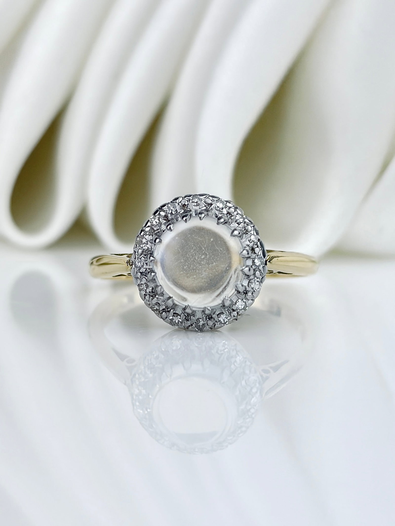 Vintage c.1965 18ct Gold Cabochon Moonstone and Diamond Halo Ring: Vintage c.1965 18ct Yellow Gold Cabochon Moonstone and Diamond Halo Ring Entrancing blue hued moonstone set in18ct white gold with the prettiest diamond halo surround! The band is yellow gold, setting