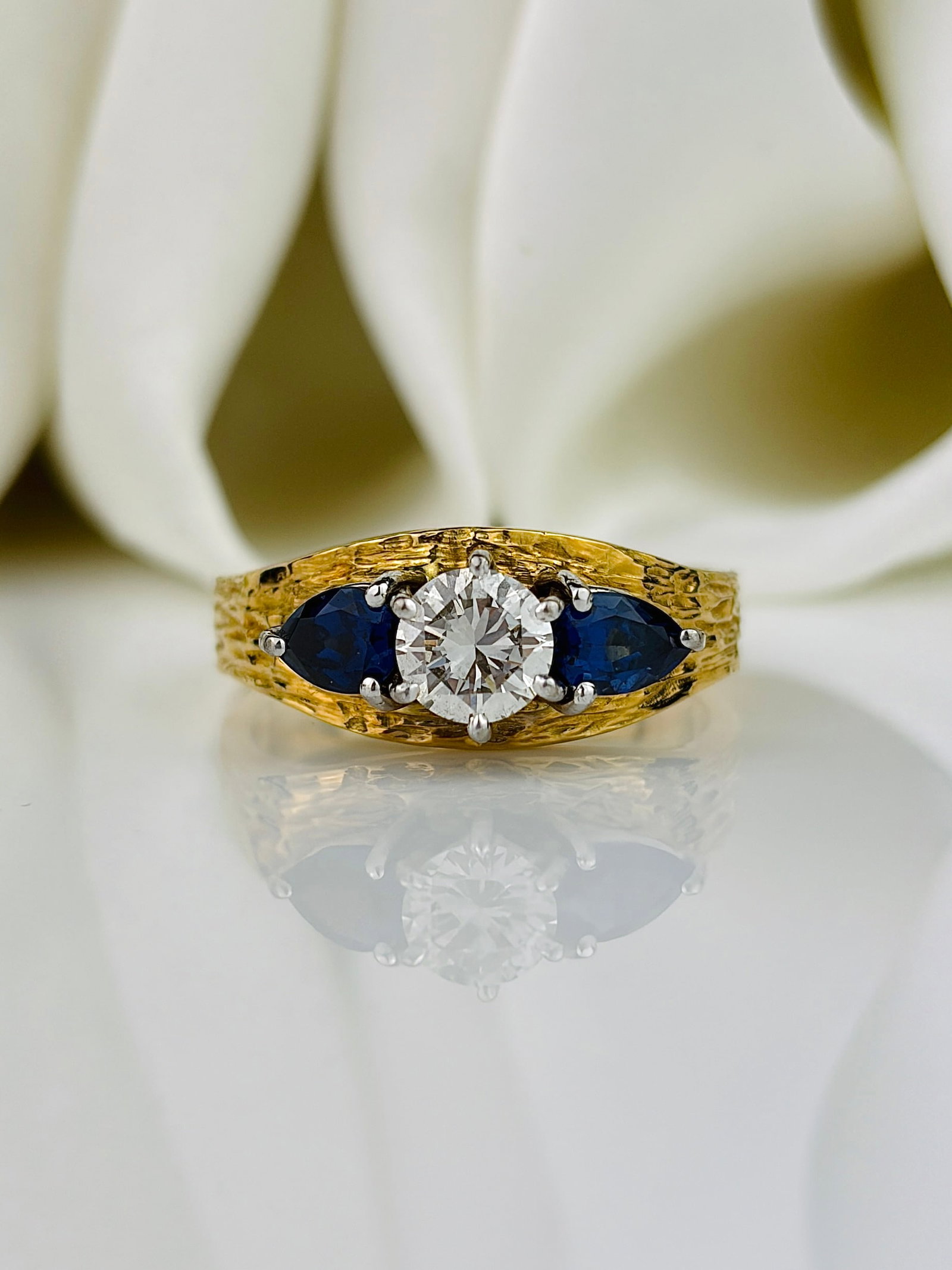 Modern Sapphire and Diamond 18ct Gold and Platinum Three Stone Ring: Modern Sapphire and Diamond 18ct Gold and Platinum Three Stone Ring Stunning textured 18ct gold band and sparkling stones set in platinum! The diamond measures 75pts and the sapphires measure 30pts