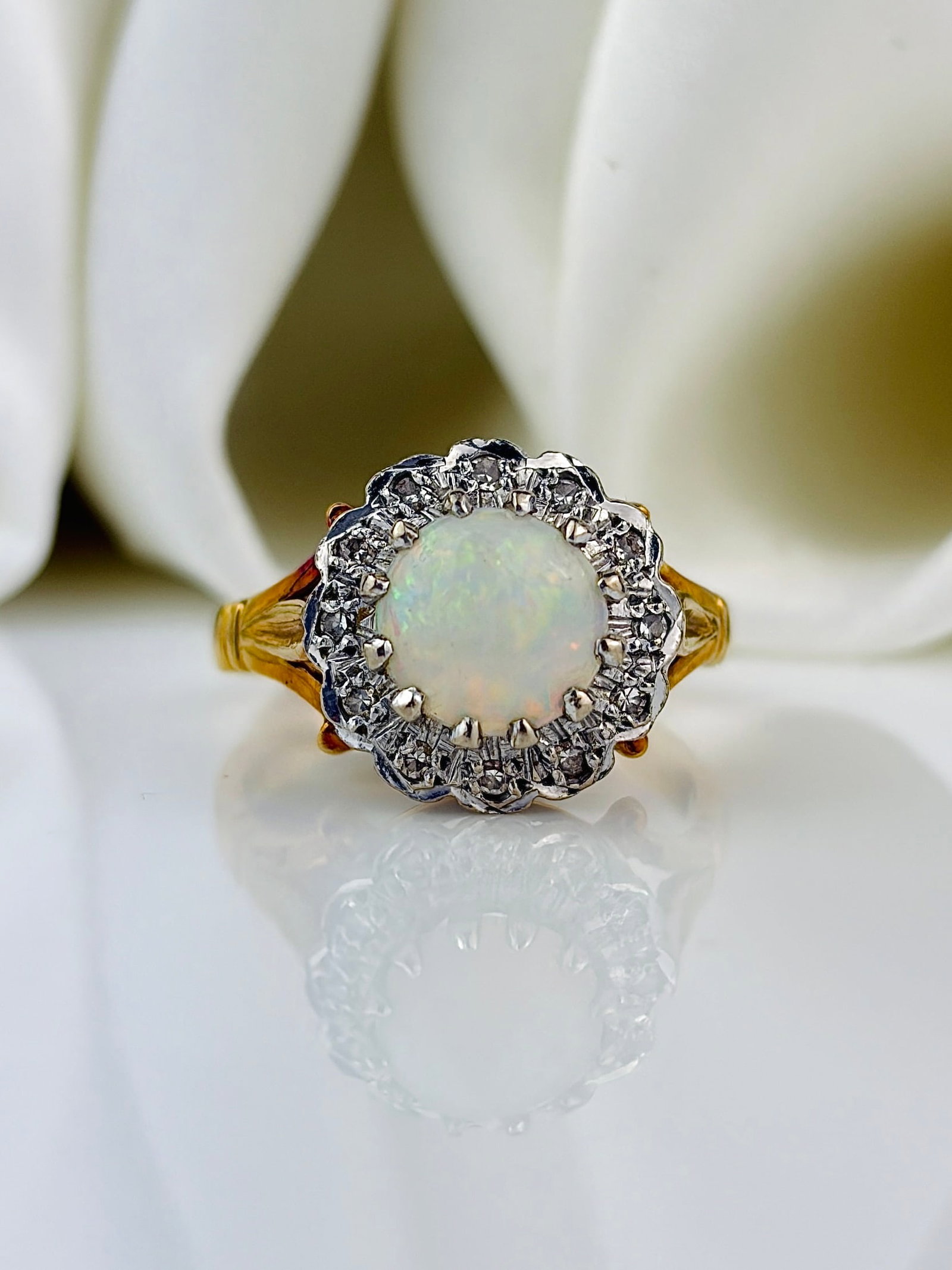 Vintage Opal and Diamond 18 Carat Gold Cluster Ring: Vintage Opal and Diamond 18 Carat Gold Cluster Ring Sat at the centre of a sparkling halo of diamonds is a gorgeous opal. The opal has wonderful hues of fiery red which glow under any light. The ring 