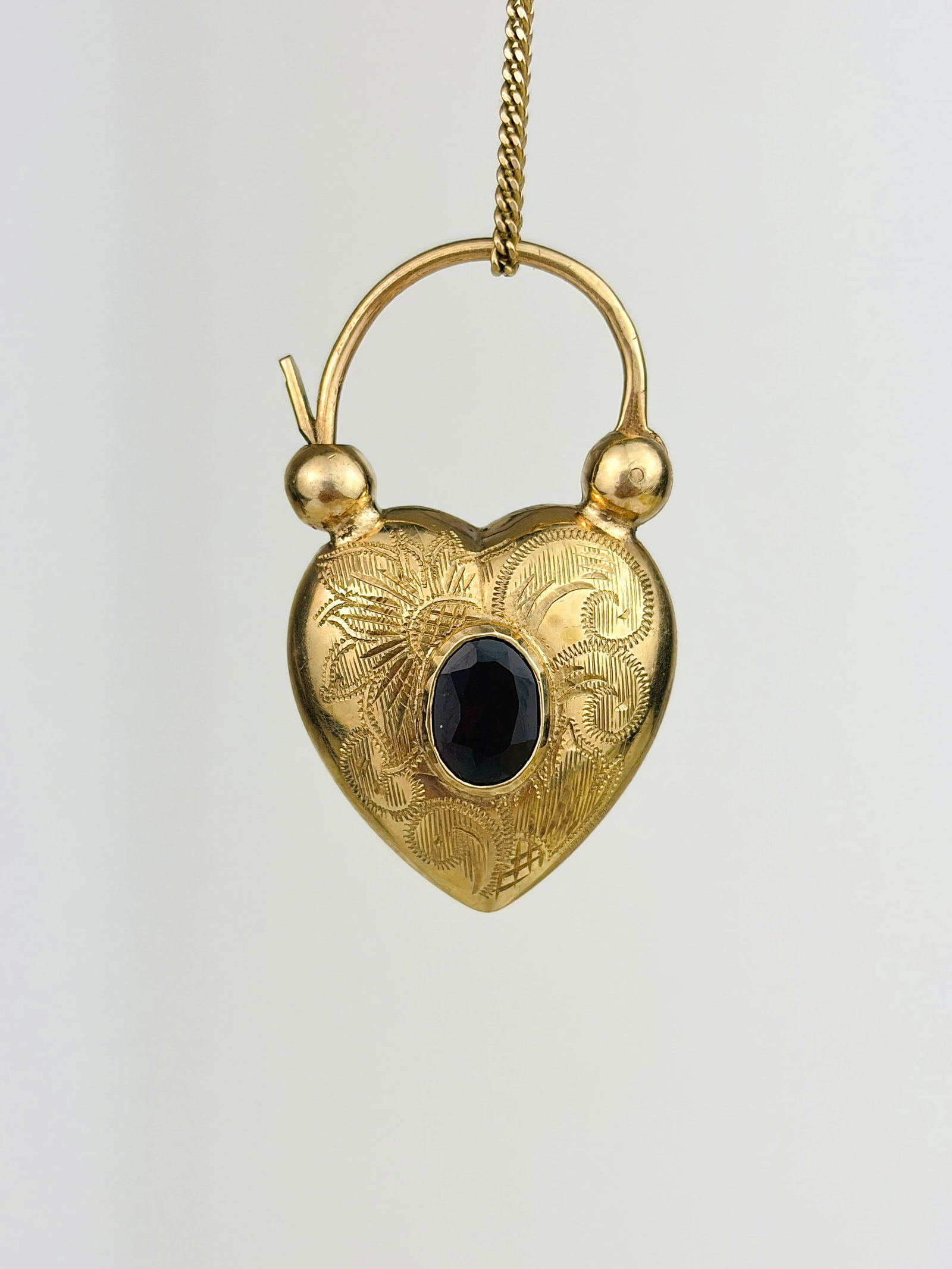 Antique 9ct Yellow Gold Garnet Engraved Puffed Heart Padlock Pendant: Antique 9ct Yellow Gold Garnet Engraved Puffed Heart Padlock Pendant The most endearing little heart padlock with a central garnet, and engraved details! Weight: 4.27g Size: 34x20x9mm Materials: