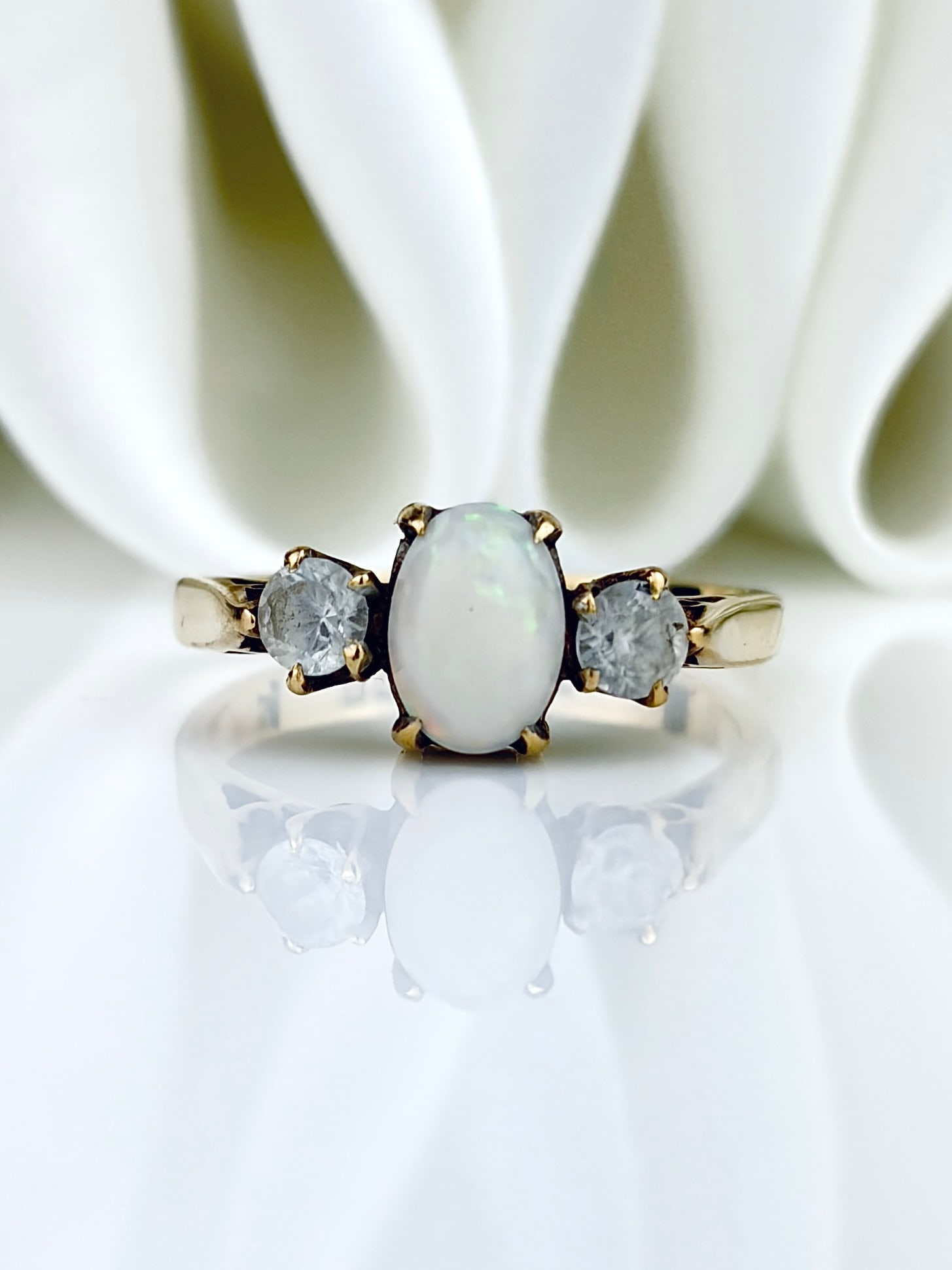 VINTAGE C.1966 18CT YELLOW GOLD OPAL AND DIAMOND WHITE SAPPHIRE THREE STONE RING: VINTAGE C.1966 18CT YELLOW GOLD OPAL AND DIAMOND WHITE SAPPHIRE THREE STONE RING Weight: 3.28g Size: UK L, US 6, Width 6mm, height off finger 5mm Materials: 18ct yellow gold, sapphire,