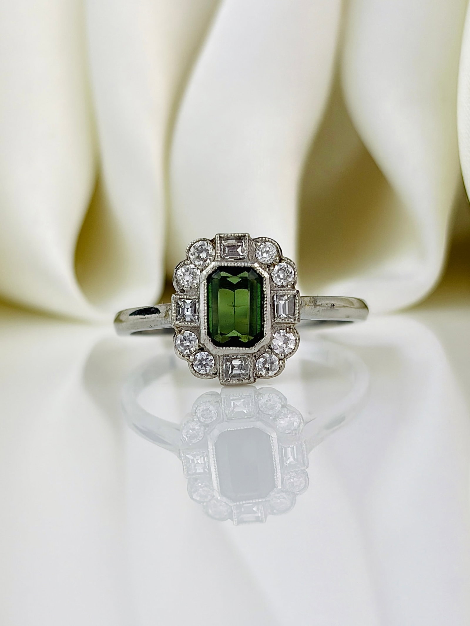 Art Deco Era Green Tourmaline and Diamond Ring In Platinum: Art Deco Era Green Tourmaline and Diamond Ring In Platinum This gorgeous tourmaline is a deep green colour and measures approx 50pts. This stone is surrounded by square and round cut diamonds totallin