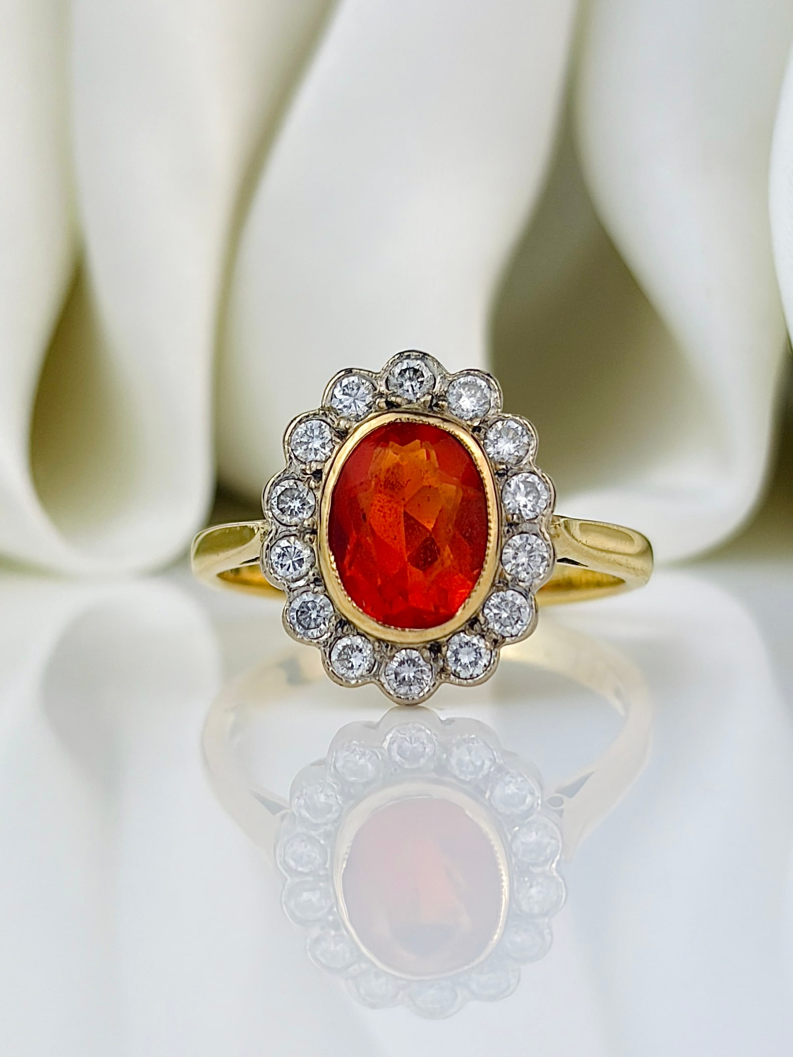 Vintage Fire Opal and Diamond 18 Carat Cluster Ring: Vintage Fire Opal and Diamond 18 Carat Cluster Ring Fire opals are the most striking bright orange colour. This oval faceted stone is 7.3mm long and surrounded by beautiful and sparkling round brillia