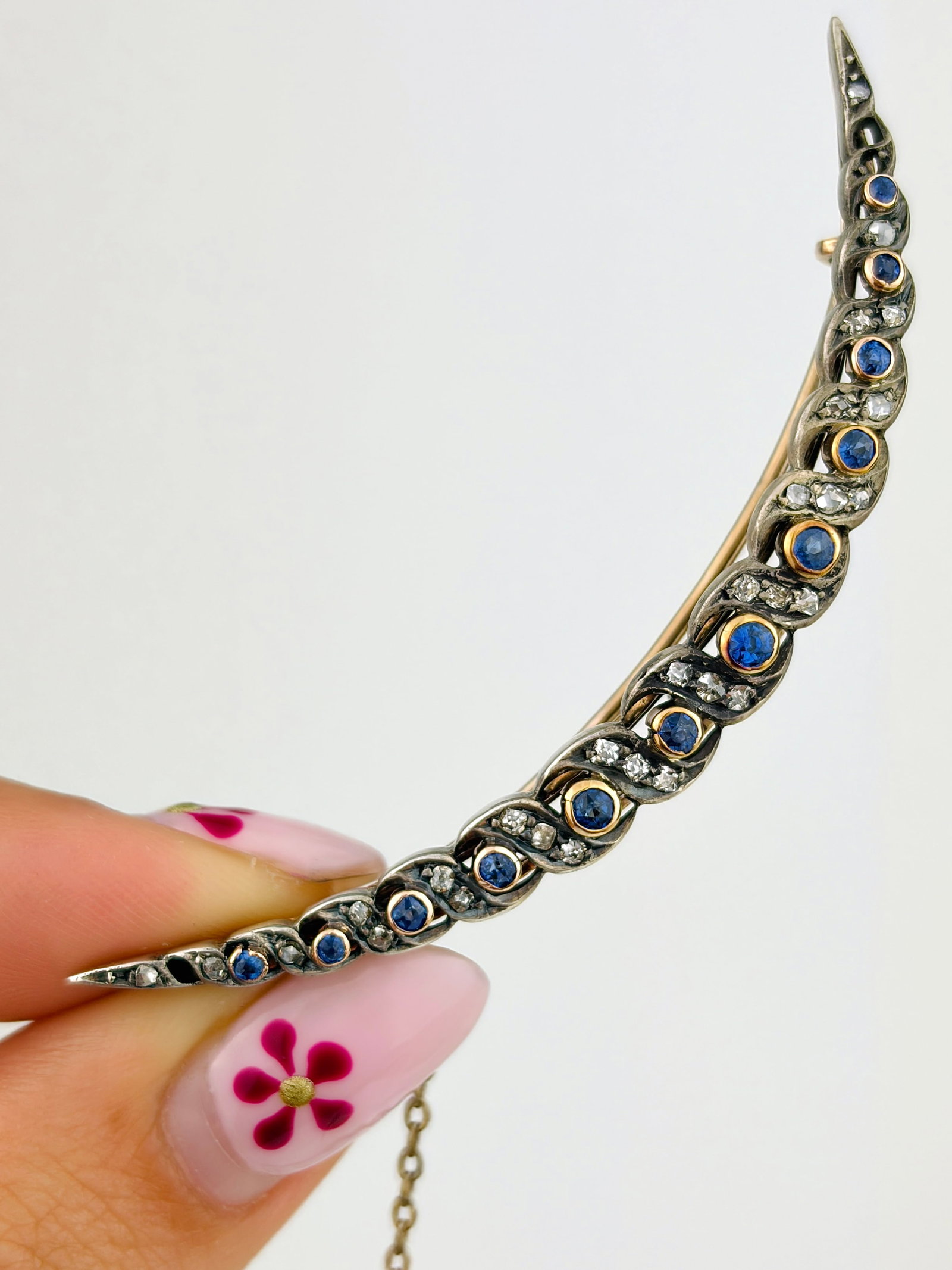 ANTIQUE EDWARDIAN SAPPHIRE AND DIAMOND TWIST CRESCENT BROOCH IN GOLD: ANTIQUE EDWARDIAN SAPPHIRE AND DIAMOND TWIST CRESCENT BROOCH IN GOLD A beautiful and unusual crescent brooch set with brigh t blue sapphires and diamonds. Weight: 6.92g Size: 5x63mm Materials: