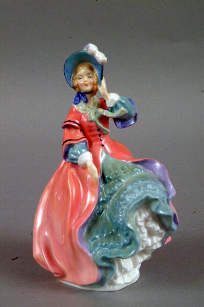 Royal Doulton "Spring Morning": Royal Doulton "Spring Morning" HN1922, modeled as a beauty holding her bonnet, painted with a pink coat, aqua skirt and black bonnet, the base stamped in green with company logo, Spring Morning, signe