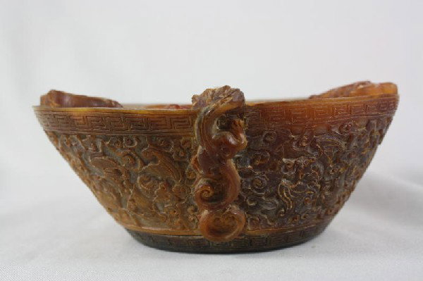 Chinese Archaistic Horn Libation Cup: Chinese archaistic horn libation cup, of typical triangular shape with the exterior carved and undercut with auspicious dragon and bats repeated in the shallow interior, the horn of rich mottled reddi