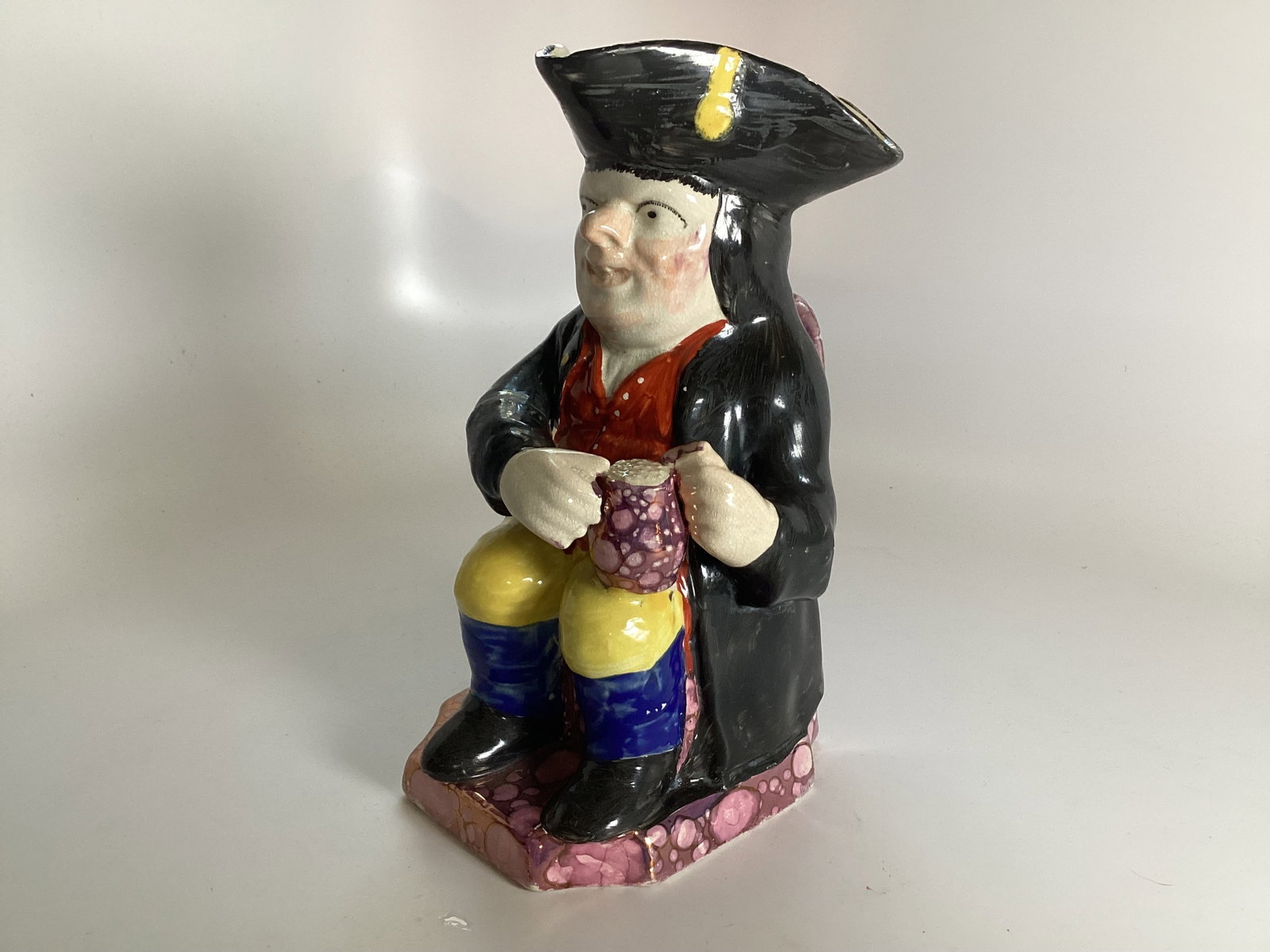 English Staffordshire Pink Splash Lustre Toby Mug C1850: Depicting a seated gentleman holding a tankard with polychrome enameled decoration. 9.5" tall. Rim chip on left side of black hat; otherwise, good condition.