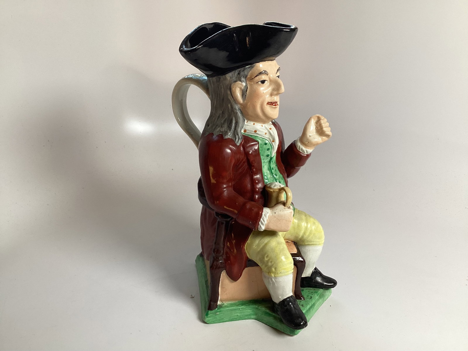 Large English Staffordshire Toby Mug of a Gentleman: Depicting a seated gentleman holding a tankard with polychrome enameled decoration. 11" tall. Good condition.