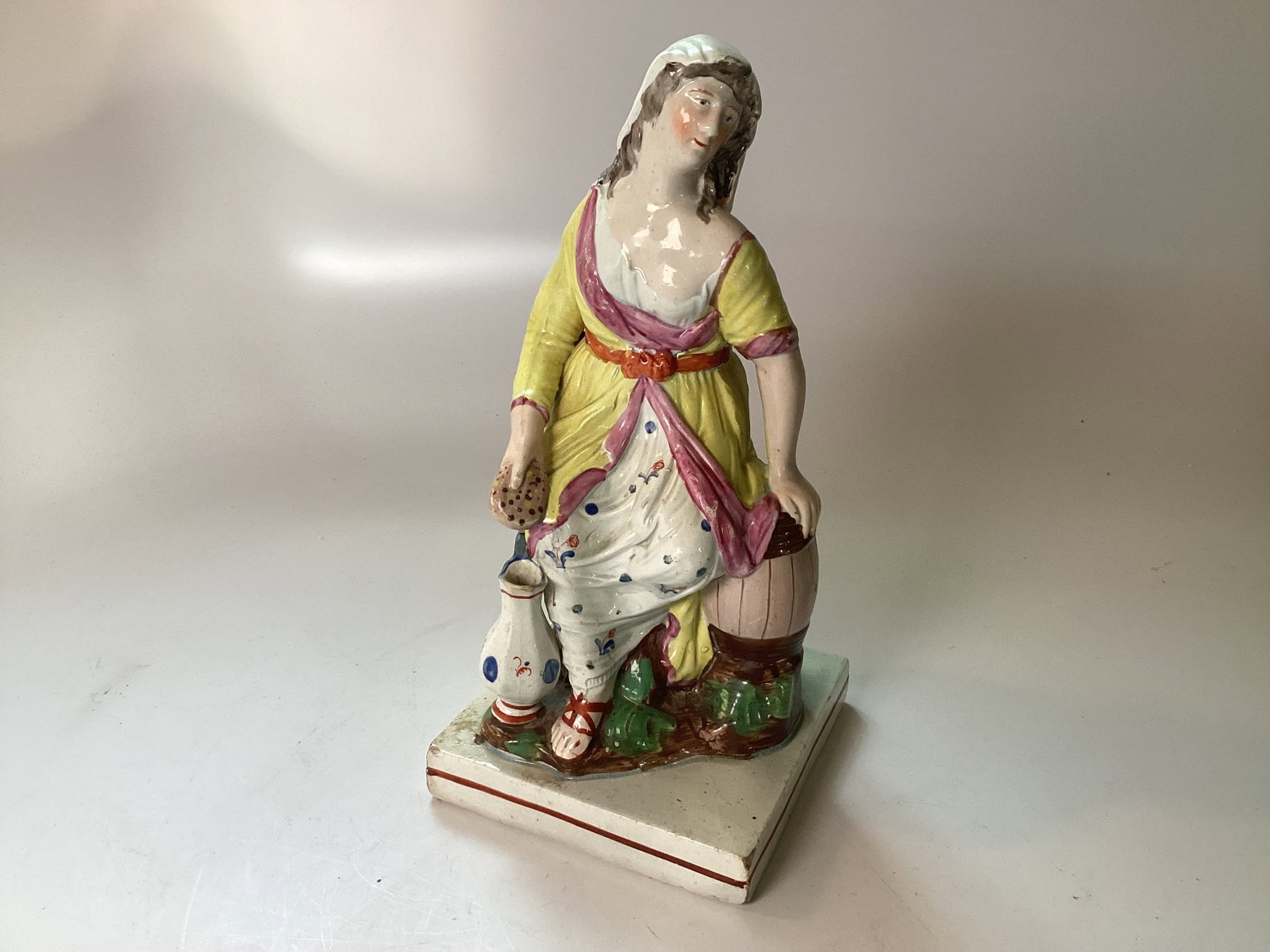 Enoch Wood Pearlware Staffordshire Figure of WIDOW OF ZAREPHATH c1820: 9" tall. An excellent and fine example with overall polychrome decoration featuring the Widow seated with an urn at her feet leaning on a barrel. Very minor edgewear.