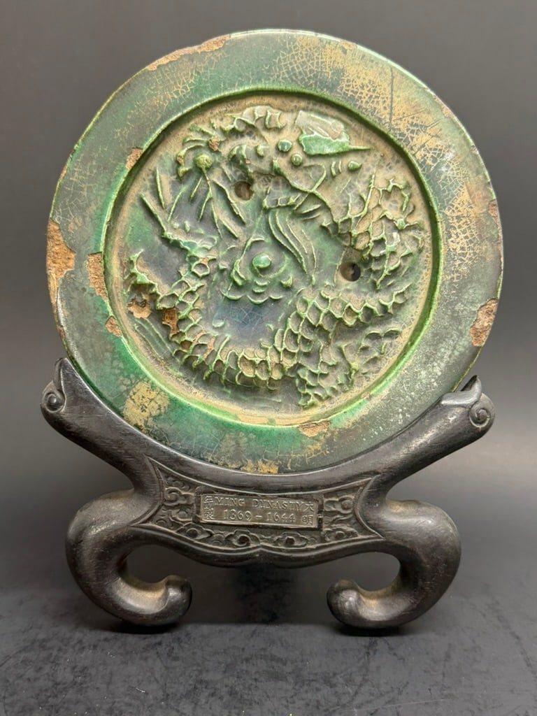 Chinese Ming Dynasty Green Porcelain Roof Tile and stand.: Chinese Ming Dynasty Green Dragon Porcelain Roof Tile and stand. The stand has a silver plaque that says Ming Dynasty (1369-1644) with Chinese characters in each corner. Tiles is 6 1/2" in diameter an