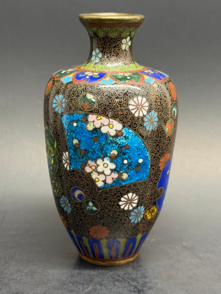 Japanese Meiji Period Cloisonne vase signed Takahara Komakichi 4 3/4": A small slightly lobed cloisonne enamel vase with roundels containing flowers and Geometric shapes amist spiral wire over black ground. Some highlights in Goldstone. Gilt wires, rim and base. Meiji Pe