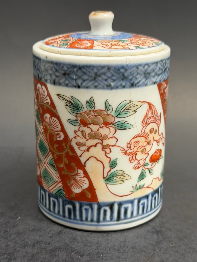 Japanese 19th Century Meiji period Imari Jar with Lid decorated with florals, geometric patterns, an: 19th Century Meiji period Japanese Imari Jar with Lid decorated with florals, geometric patterns, and foo dogs. There is an old label on the bottom indicating that this piece is from the early 17th ce