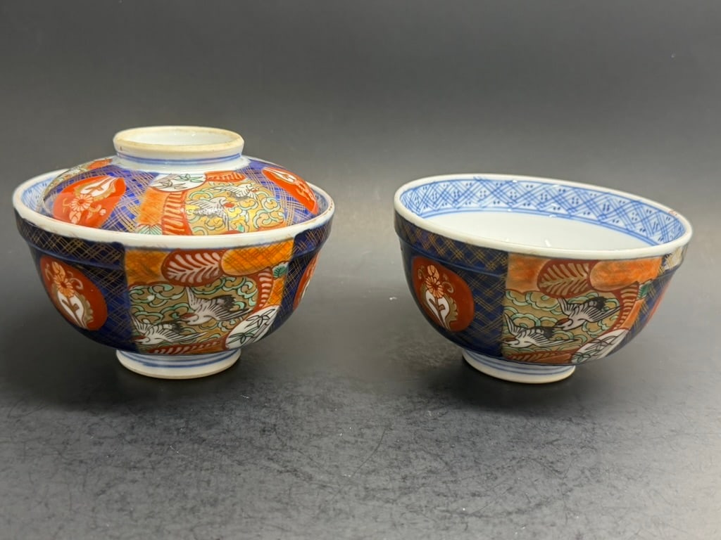 Lot of 2 Matched Japanese 19th Century Meiji Period Imari bowls Decorated with florals and cranes. O: Lot of 2 Matched 19th Century Meiji Period Japanese Imari bowls Decorated with florals and cranes. One bowl is lidded and lid has “Hizen mark. Bowls are four and three-quarter inches across by two a