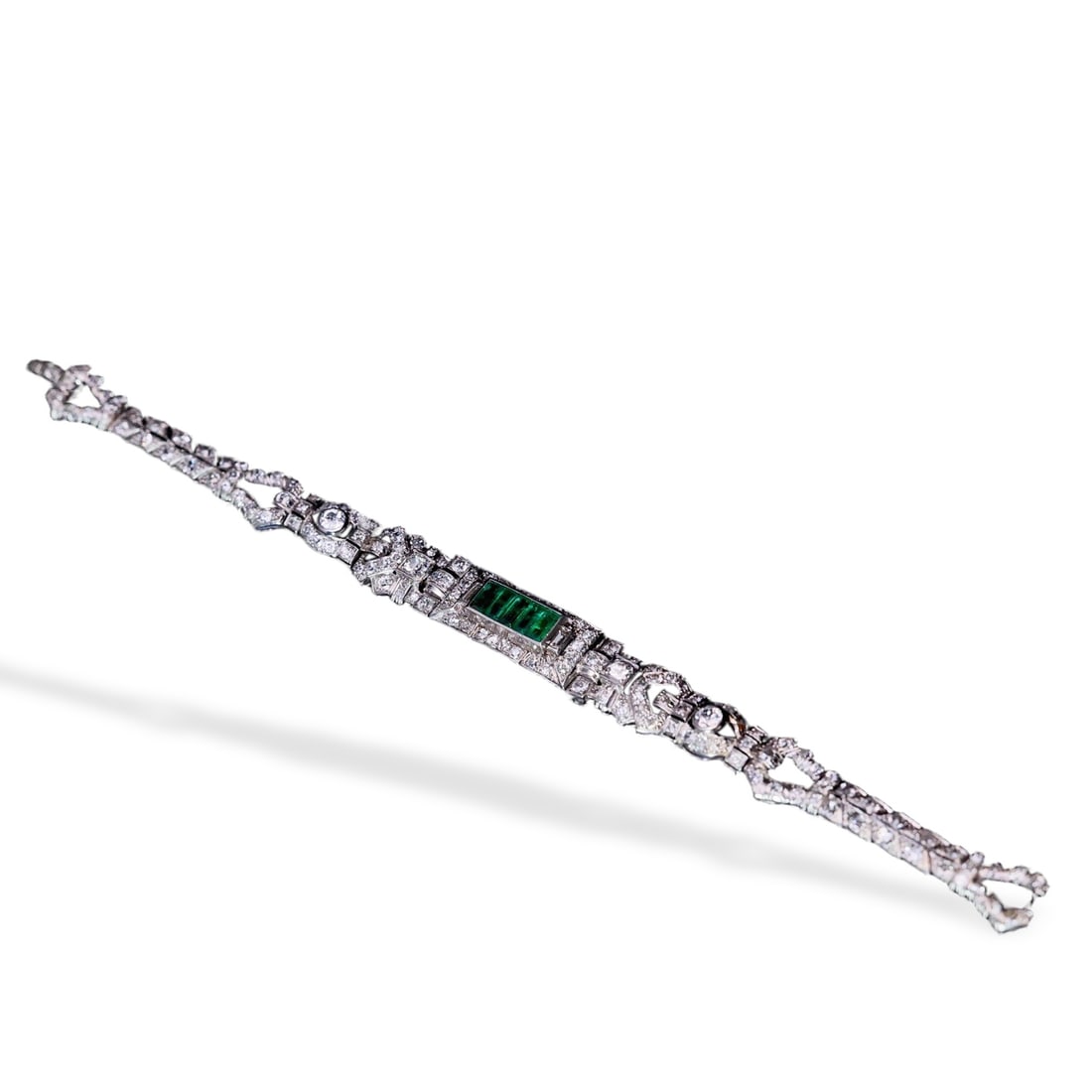 ART DECO PERIOD PLATINUM, DIAMOND AND EMERALD BRACELET: Boldly structured piece featuring a high-quality 2 ct Afghan emerald, old European and rose cut diamonds, and approximately 5 ct of baguette cut diamonds; total length 16.5 cm (6 1/2 in).