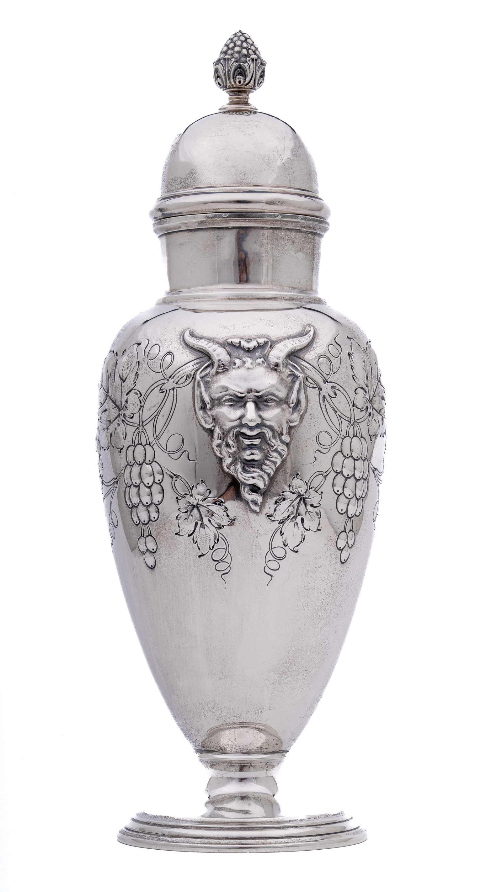 International Sterling Silver Bacchus Cocktail Shaker: A finely crafted sterling silver cocktail shaker in the Bacchus motif, featuring a bold repoussé depiction of the Roman god of wine among grapevines and foliage. The vessel has a domed lid with a sty
