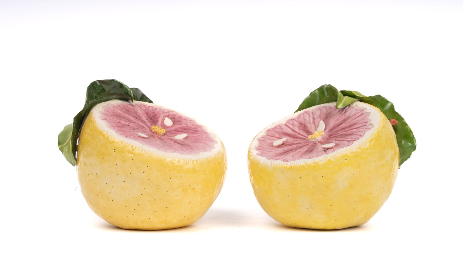 Pair Katherine Houston Porcelain Painted Grapefruit: A finely executed pair of hand-painted porcelain grapefruit sculptures by acclaimed American artist Katherine Houston. Each piece features a vividly rendered cross-section of pink grapefruit, encircle