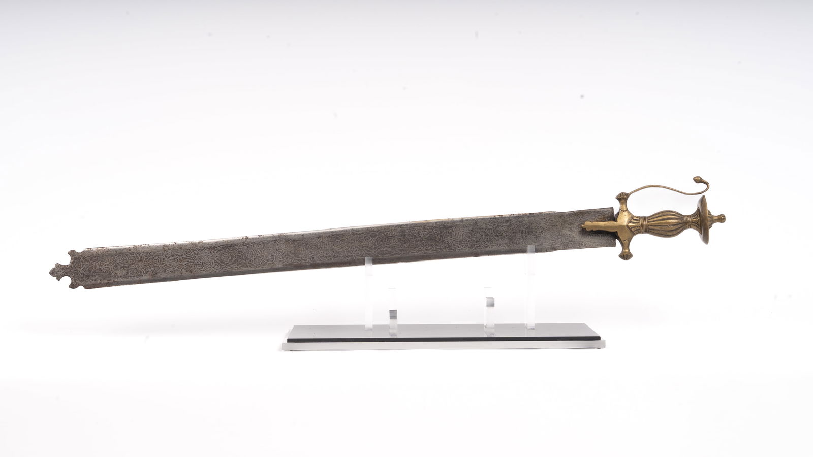 18th Century South Indian Khanda Sword with Brass Hilt and Etched Blade: Broad, straight double-edged steel blade, the surfaces etched with dense foliate and geometric ornament; the terminal formed with a distinctive notched, bifurcated tip. Cast brass hilt of South Indian