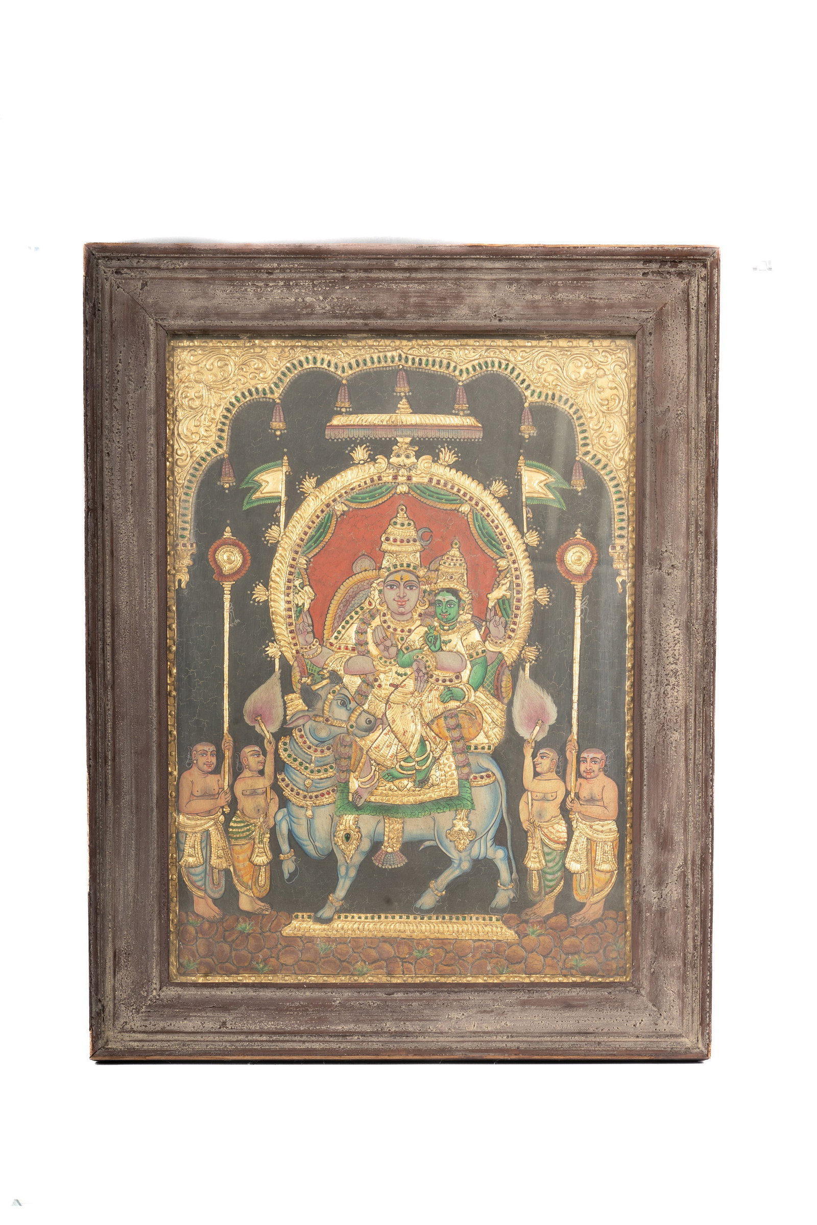 Tanjore Painting of a Deity: Finely executed South Indian Tanjore painting depicting a richly adorned deity within an arched shrine setting, embellished with gold leaf and polychrome pigments. The composition exemplifies the prec