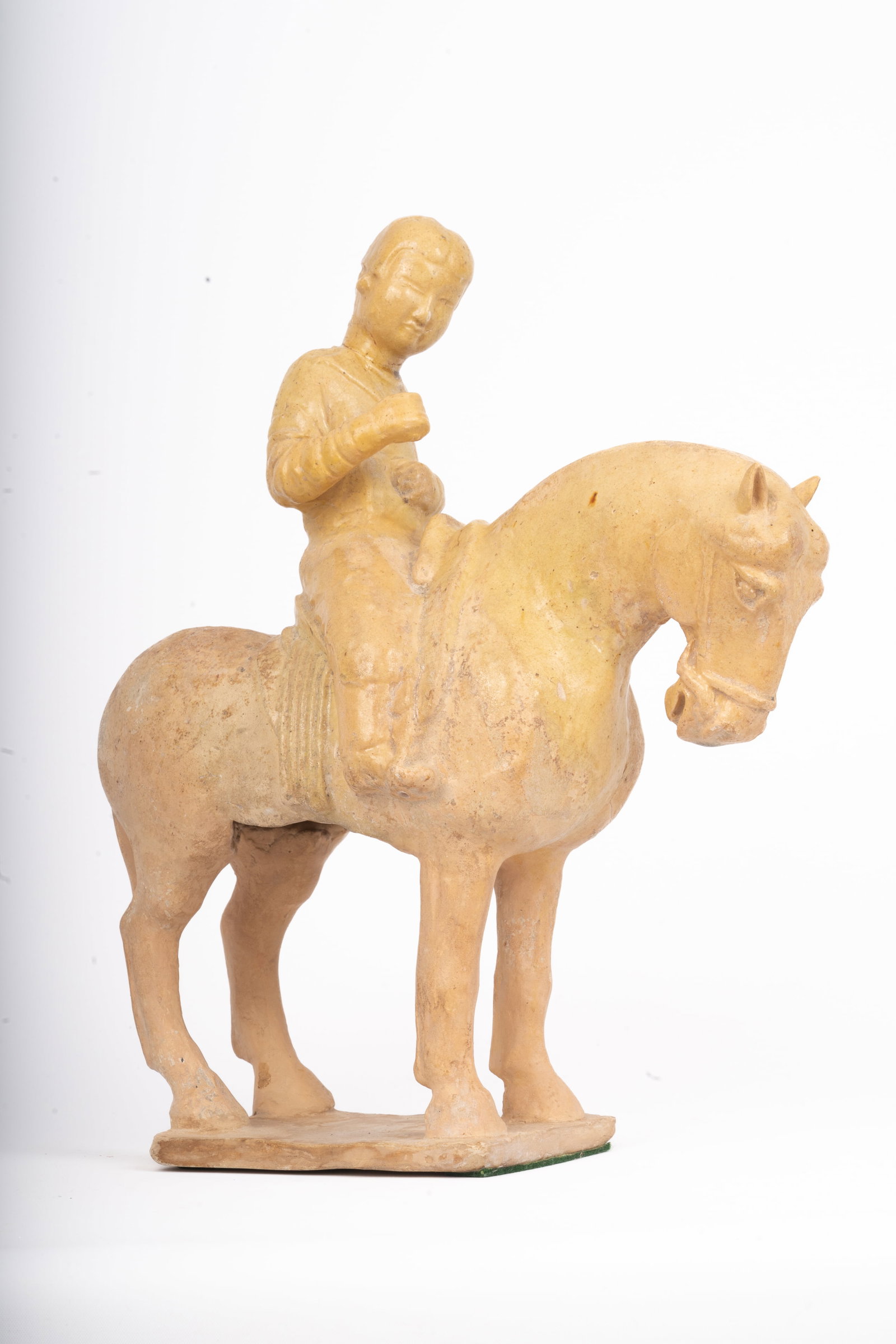 Chinese Pottery Figure of a Horse and Rider, Tang Dynasty Style: A terracotta figure modeled as a horse and rider, in the Tang dynasty style, the surfaces with ochre-toned slip simulating burial patina. The rider shown seated with one hand raised, the horse standin