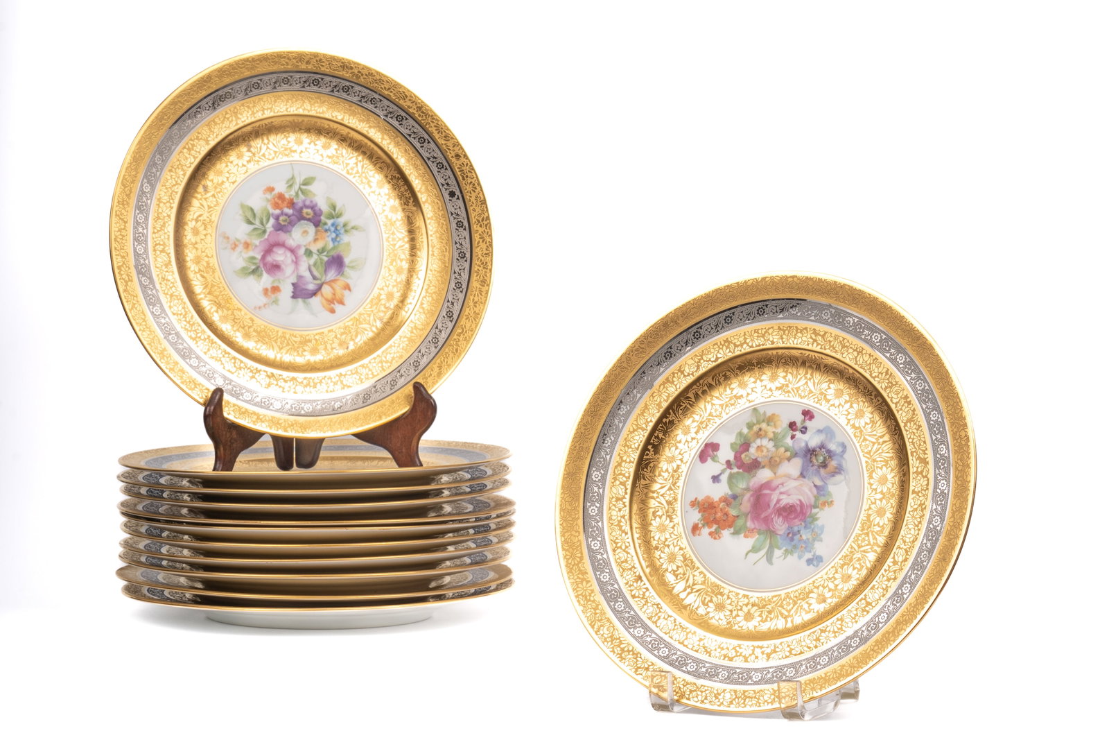 Twelve Royal Bavarian Hutschenreuther Gold and Silver Chargers: set of twelve porcelain chargers by Royal Bavarian Hutschenreuther, Selb, Bavaria, each with a central hand-painted floral bouquet within wide borders richly decorated in gilt and silver foliate bands