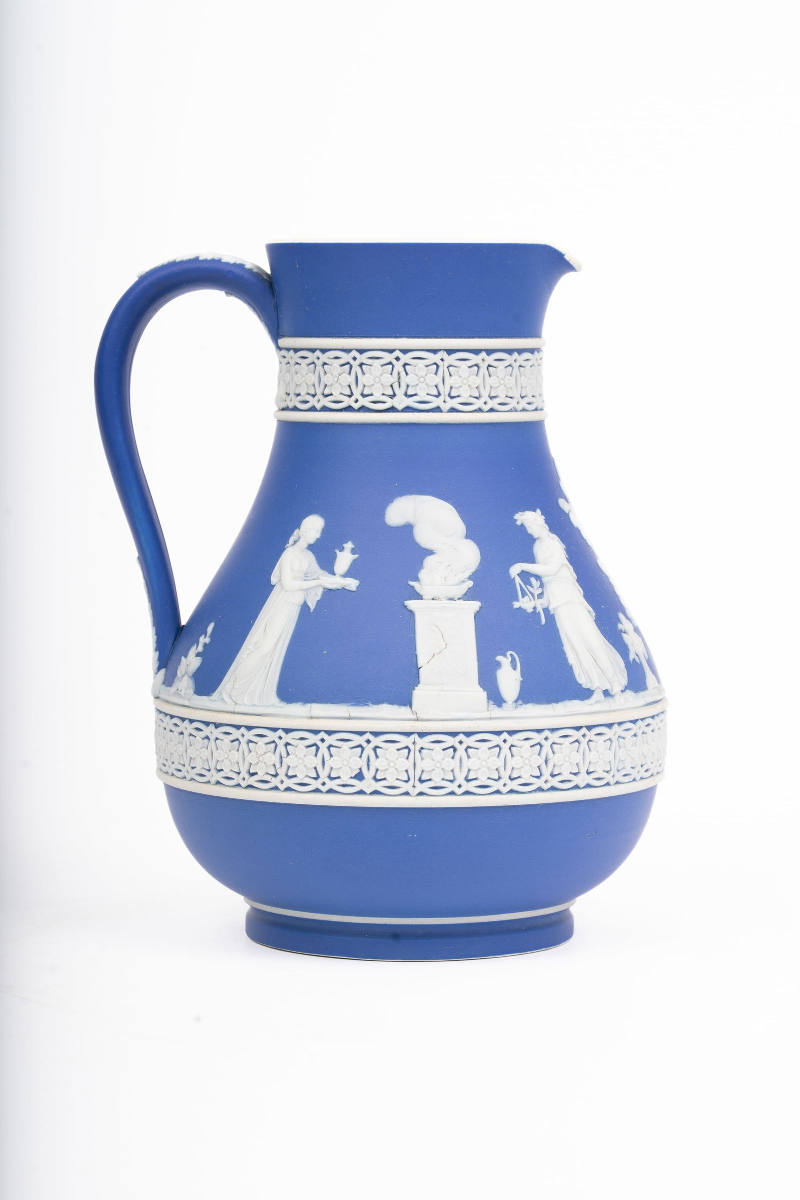 Antique Wedgwood Blue Jasperware Pitcher: A fine early Wedgwood blue jasperware pitcher, decorated in classical white relief with neoclassical figures, urns, and decorative floral borders. The piece exhibits crisp modeling and balanced propor