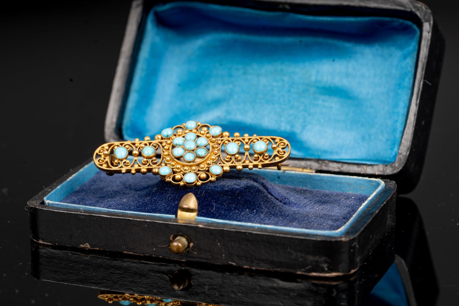 Victorian 9K Gold and Turquoise Brooch: Victorian brooch in 9K yellow gold, delicately designed with openwork scrolls and granulated detailing, set throughout with cabochon turquoise stones of varying size. The rich gold filigree and bright