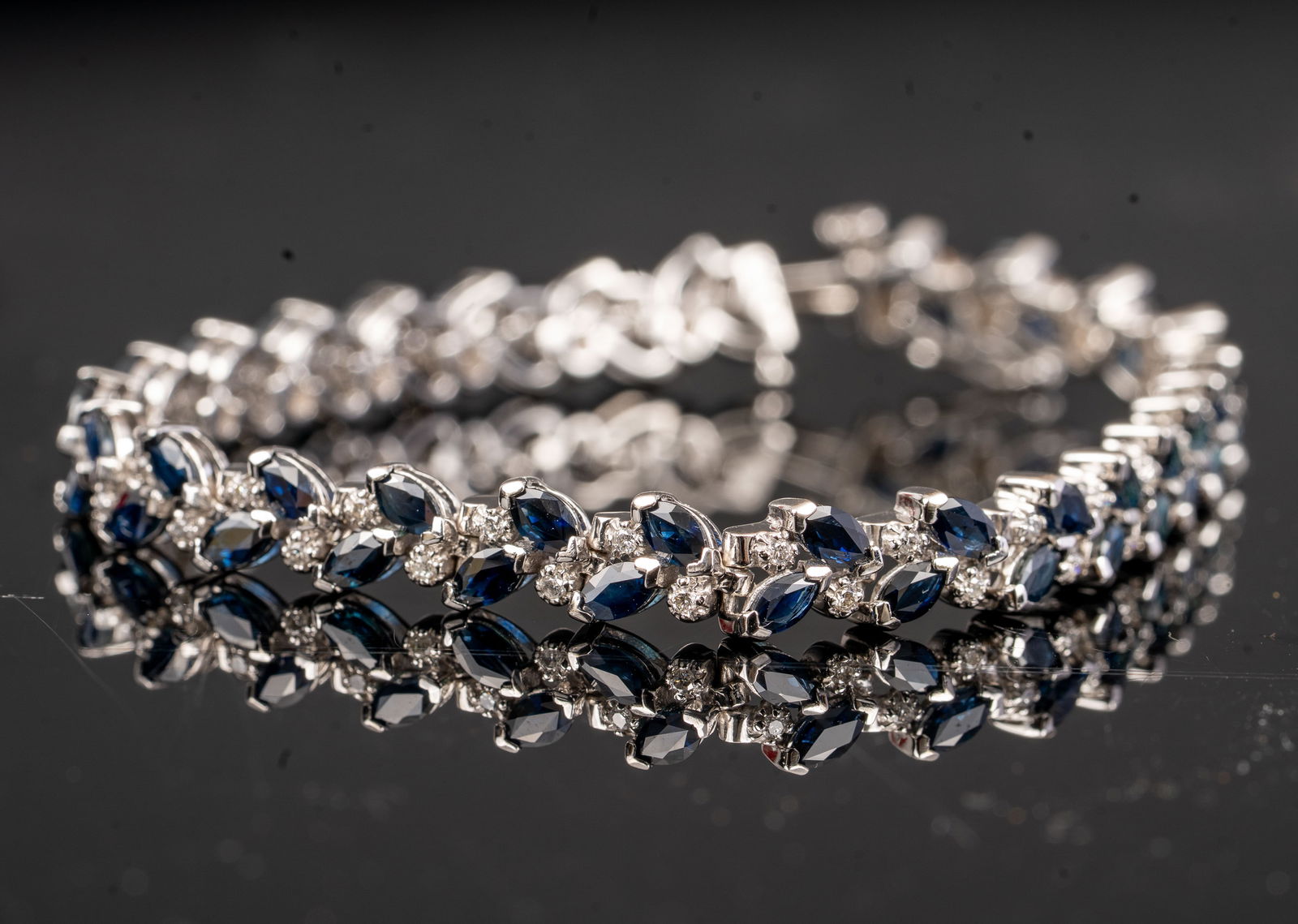 14K White Gold Diamond and Sapphire Bracelet: Elegant bracelet featuring approximately 6.00 carats of marquise-cut blue sapphires alternating with about 2.00 carats of round brilliant diamonds, all set in polished 14K white gold. The design combi