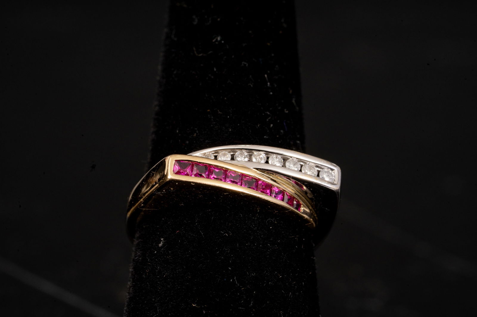Two-Tone 14k Gold Diamond & Ruby Bypass Ring: Two-tone 14k gold bypass-style ring featuring a diagonal channel of square-cut rubies and a curved row of round brilliant-cut diamonds set in white gold. The sculptural crossover design creates a mode