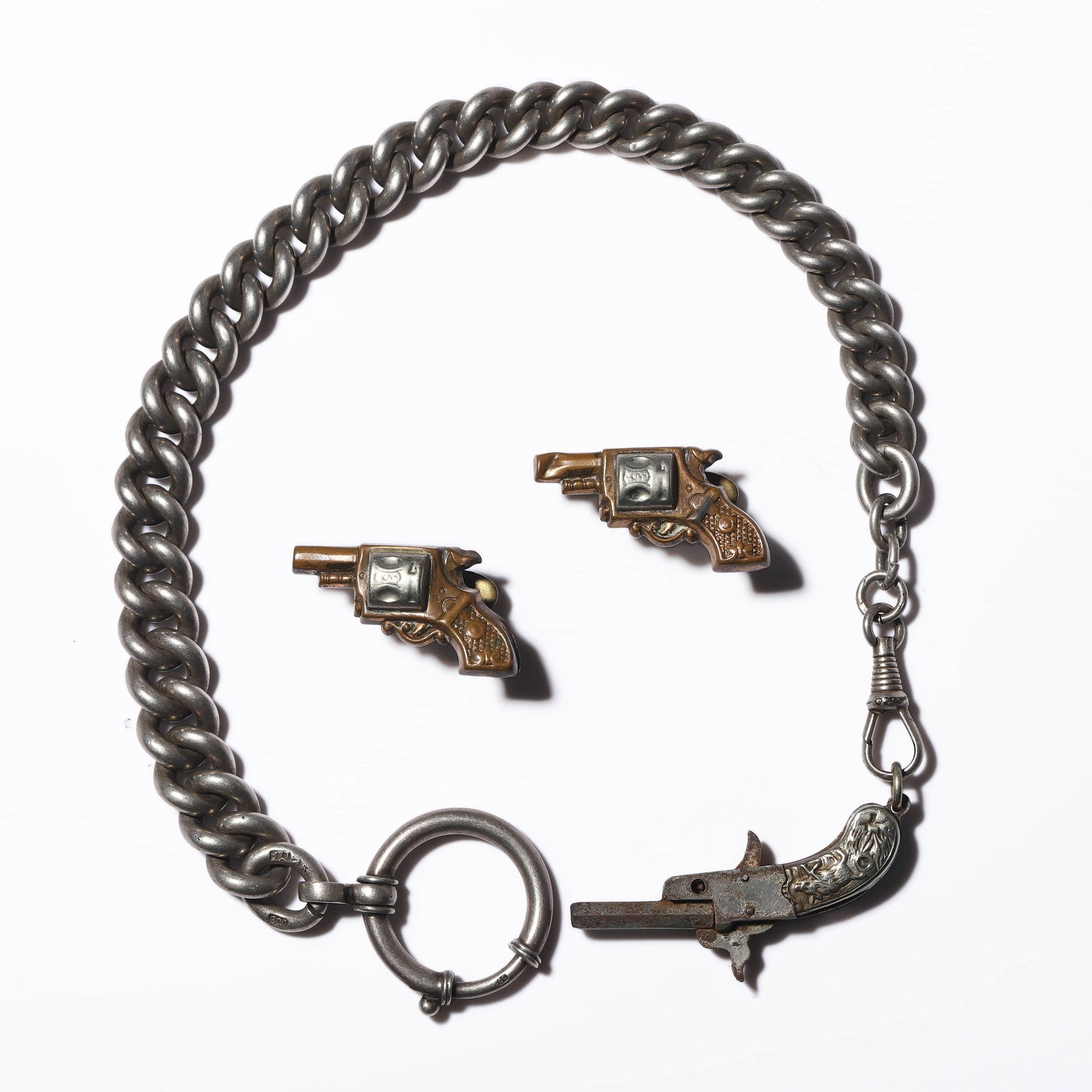 GERMAN, CIRCA 1940 — A SILVER WATCH CHAIN WITH PISTOL-FORM CUFFLINKS.: GERMAN, CIRCA 1940 — A SILVER WATCH CHAIN WITH PISTOL-FORM CUFFLINKS. Medium: Silver and gilt metal ?Dimensions: Chain length: 13 in. (33 cm); Cufflinks length: 1 3/16 in. (30 mm); Total weight: 76 